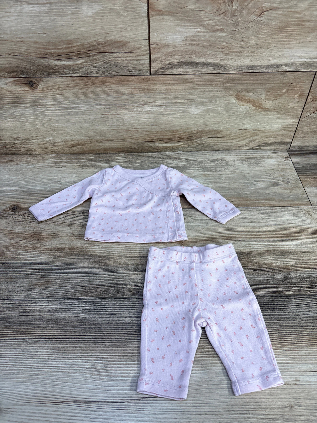Pink baby long-sleeve shirt and pants set with tiny floral print on wood background