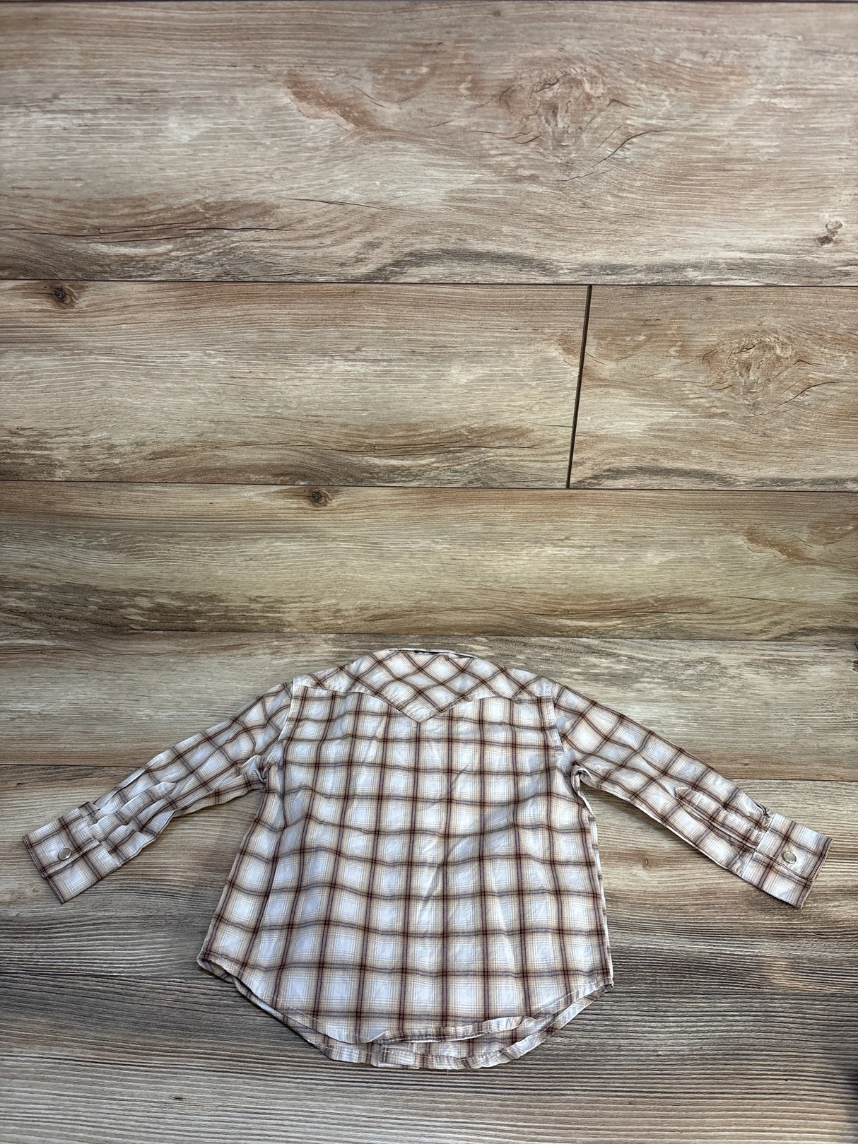 Back view of Wrangler beige plaid western snap toddler shirt, 24m, showing long sleeves, pointed yoke, curved hem on wood