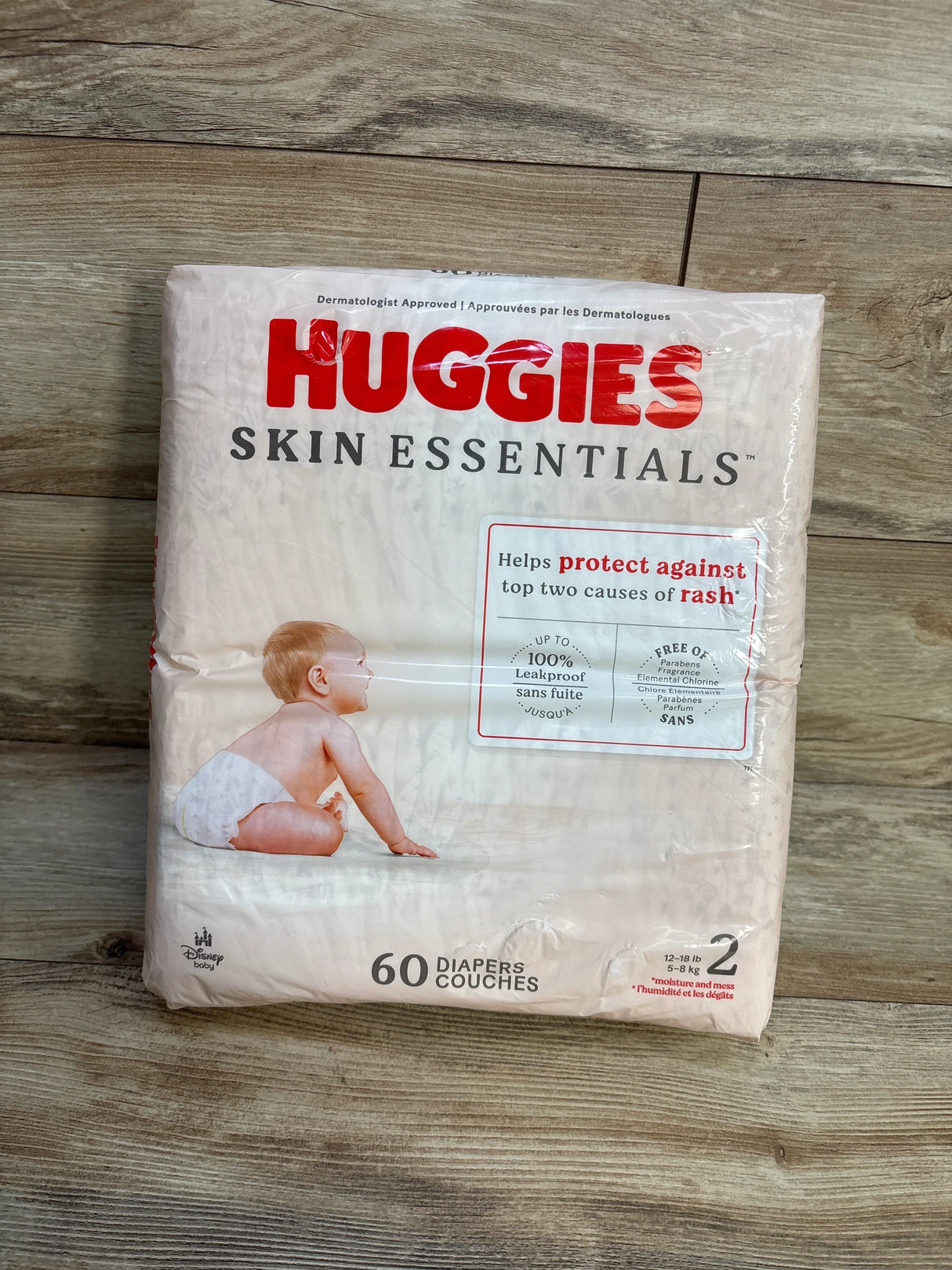 Huggies Skin Essentials size 2 diapers pack with baby image on wood floor