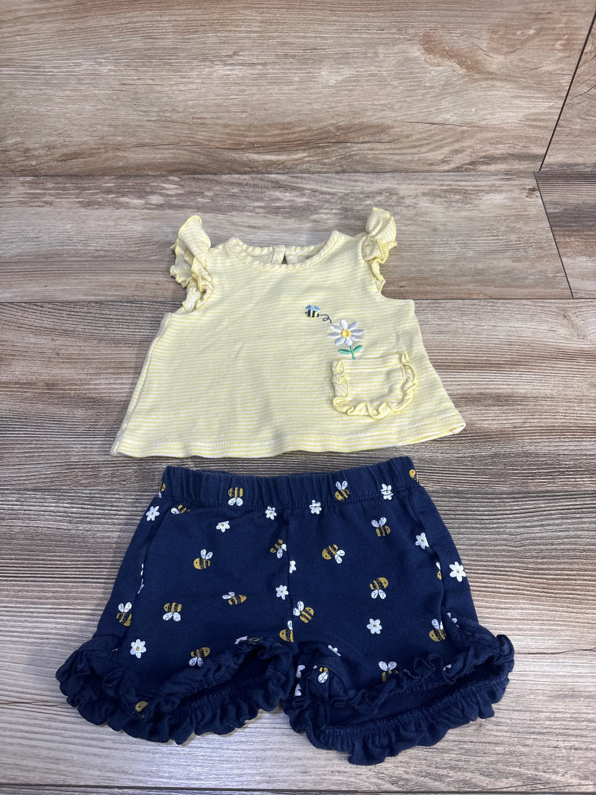 Front view of Little Me two-piece baby set showcasing a yellow ruffled tank with embroidered bee and navy bee-print shorts