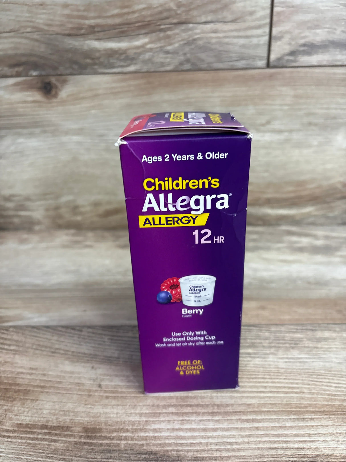 Front view of Children's Allegra 12-hour allergy box showing berry flavor and 'Ages 2 Years and Older' text on wood background