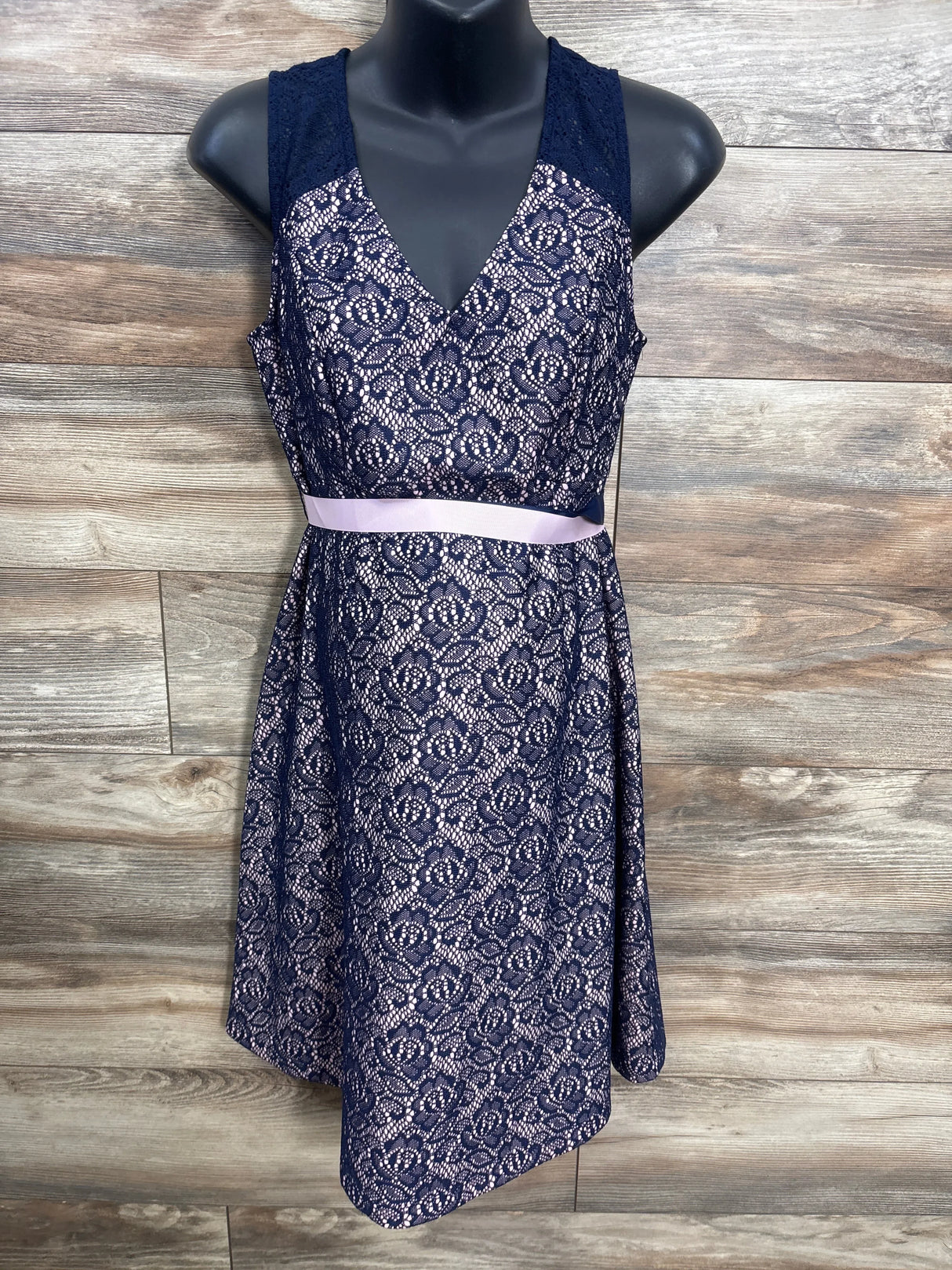 Navy blue sleeveless lace dress with pink ribbon belt on mannequin, floral pattern