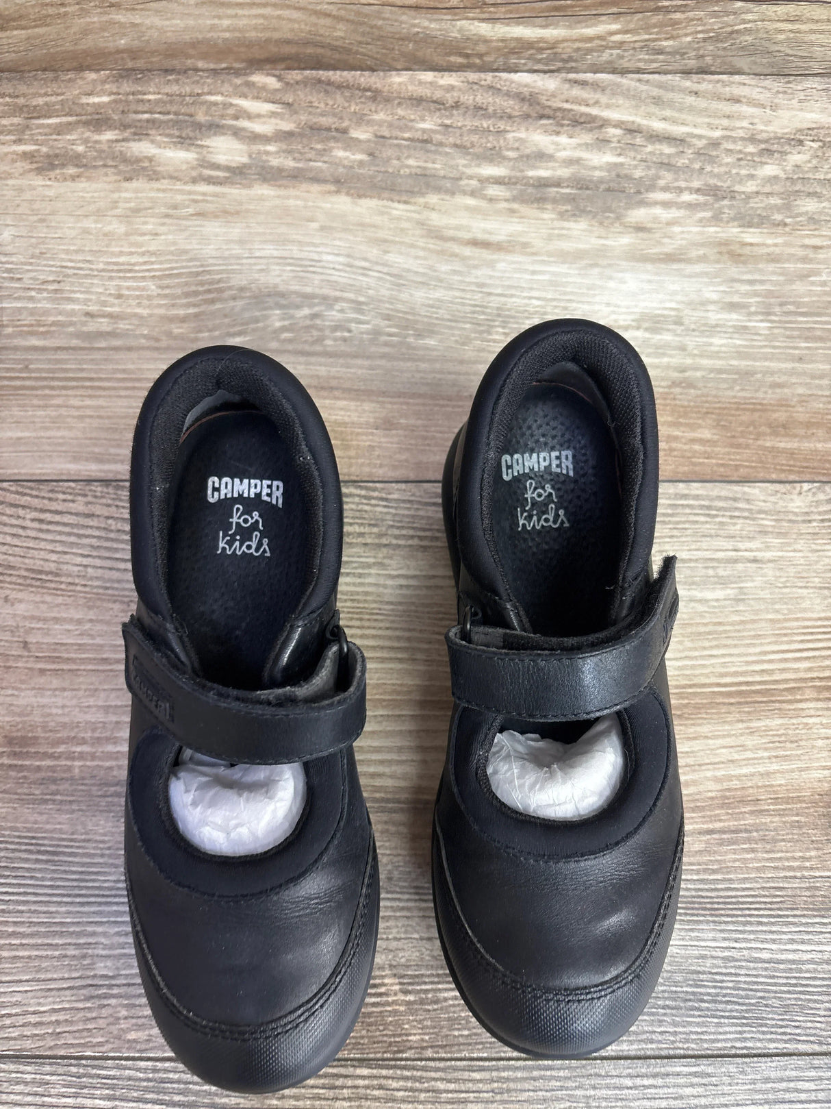Black leather Camper Mary Jane shoes for kids with Velcro straps on wood background