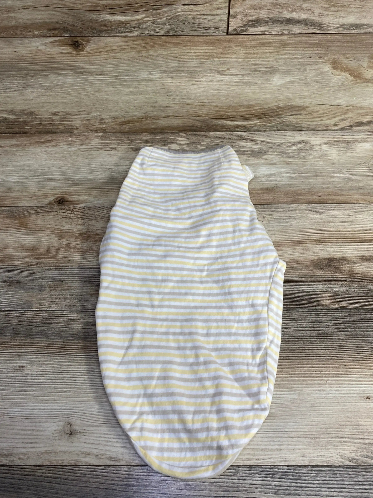 Yellow and white striped baby swaddle sack on wooden surface
