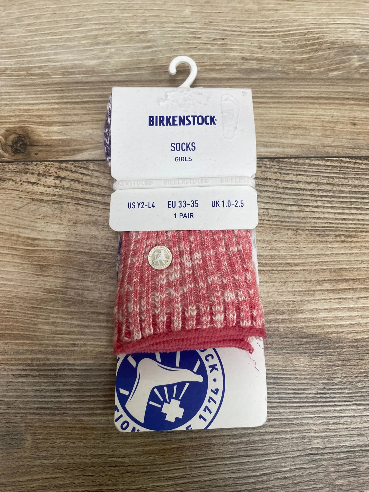 Top down view of girls Birkenstock ankle socks in desert rose marled knit packaged with white Birkenstock size tag on wood background