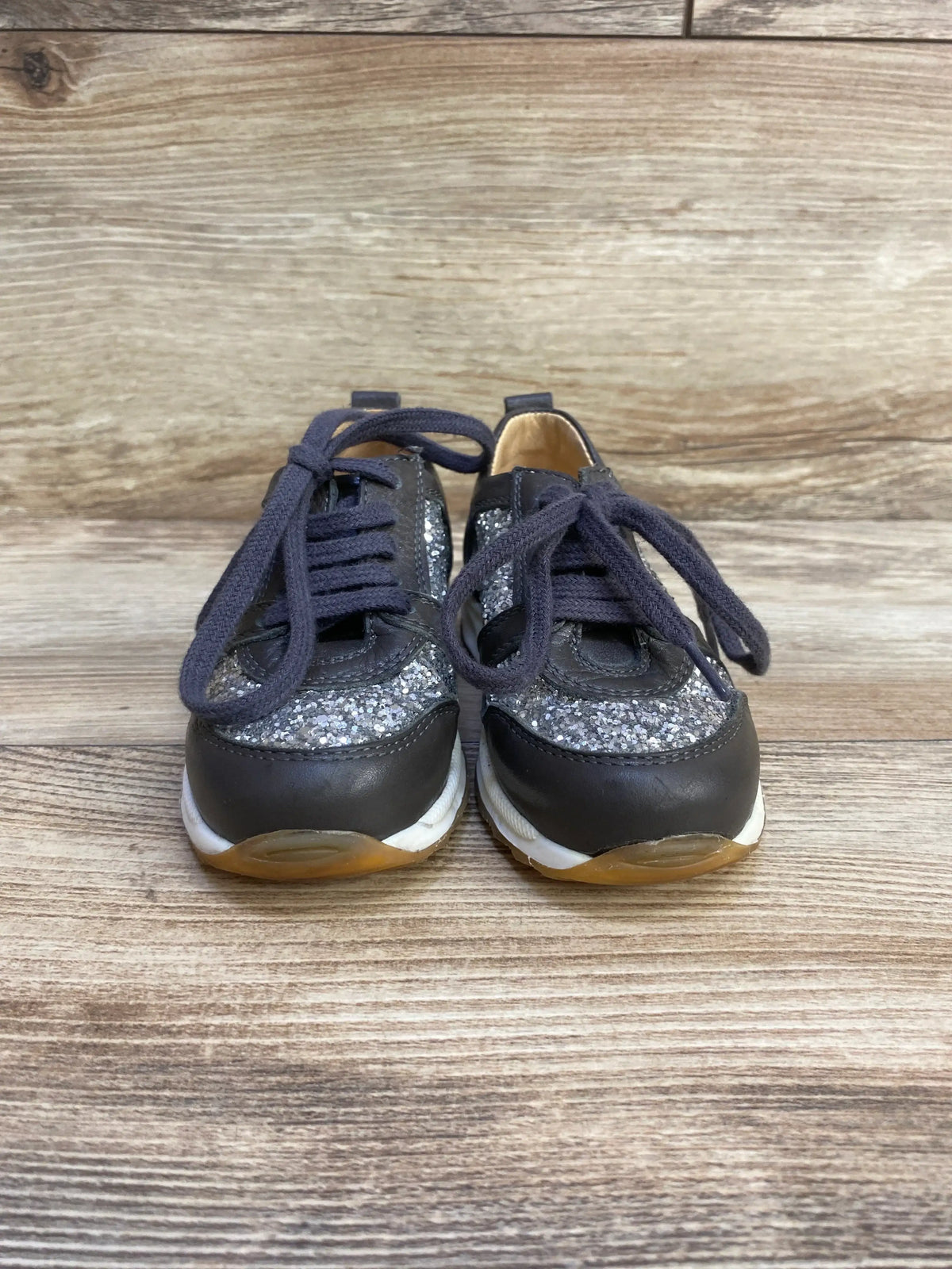Front view of Angulus Glitter Sneakers size 7c showcasing gray silver glitter panels with dark gray leather toes and laces on wood plank floor