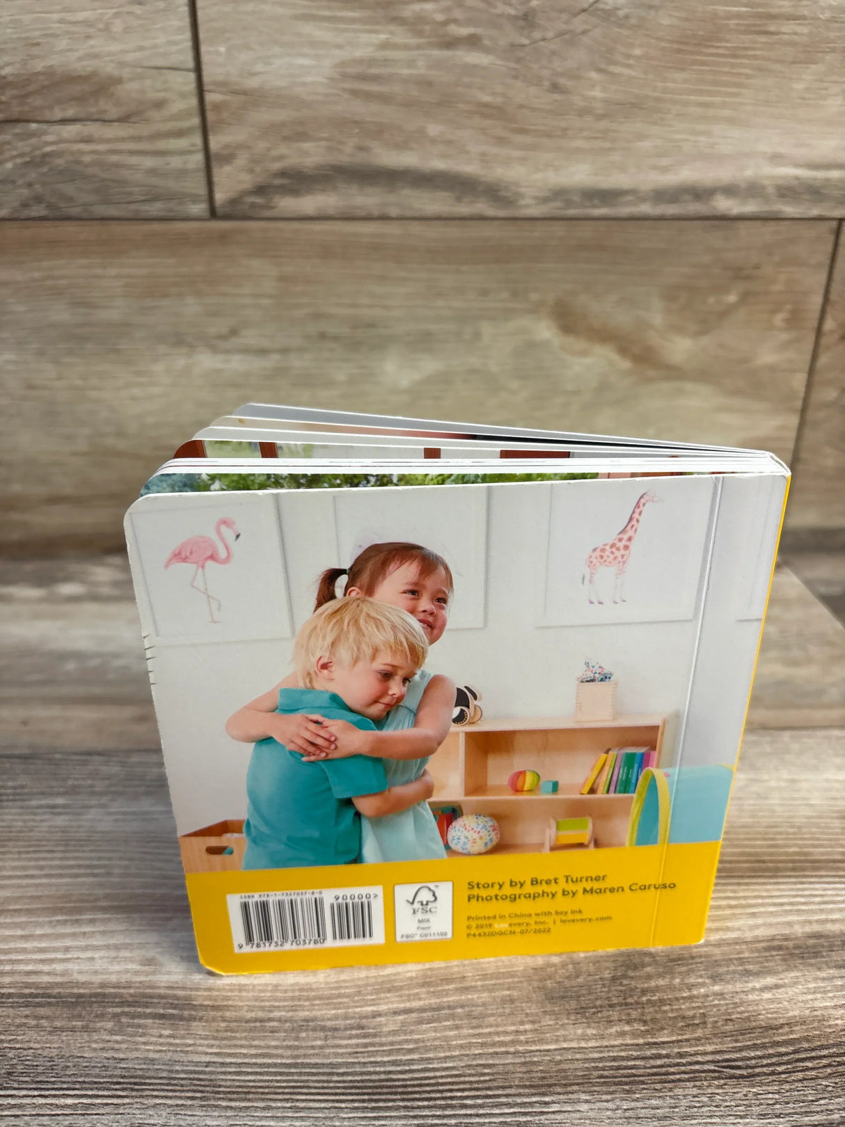 Children's board book with kids hugging, flamingo and giraffe illustrations, ideal for baby and toddler learning