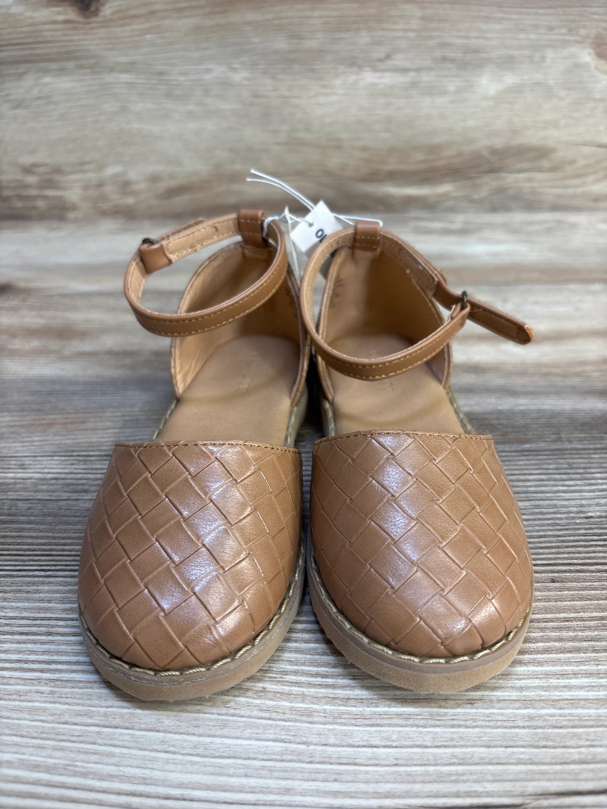 Brown woven faux leather girls' closed-toe sandals with ankle straps on wooden background