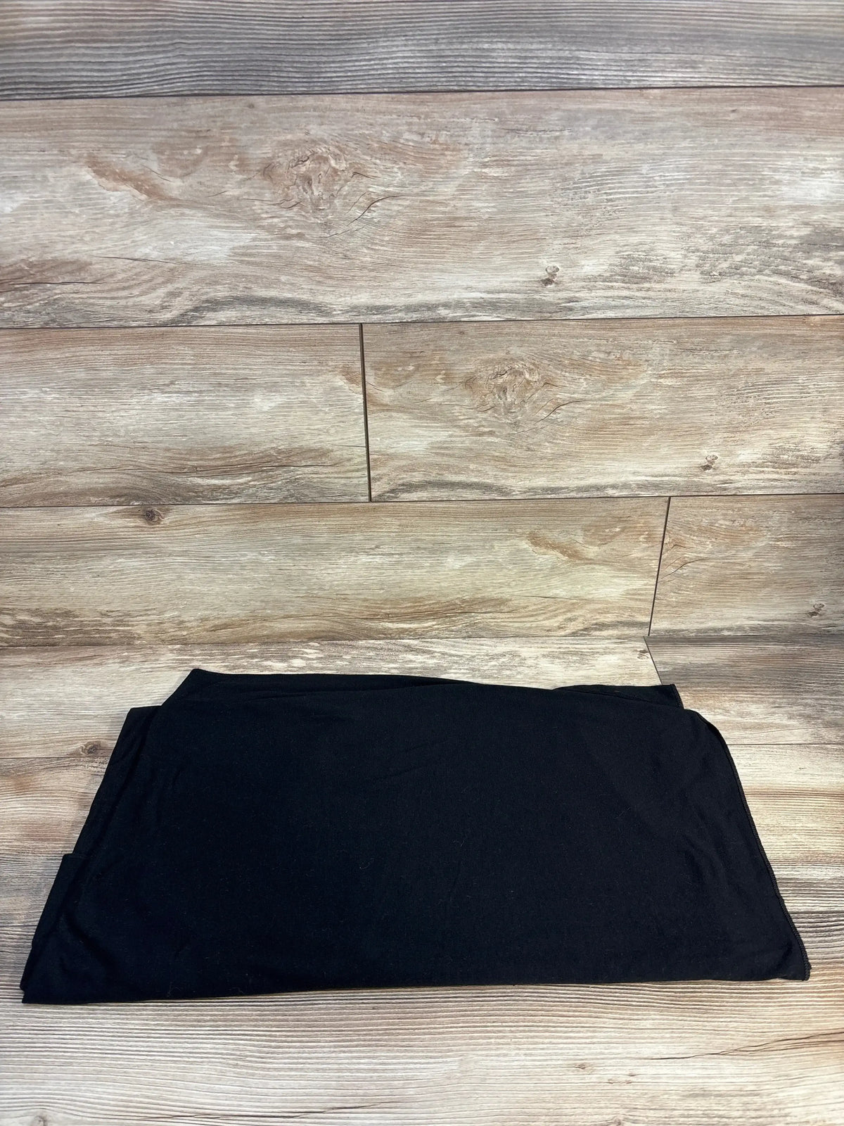Folded black Copper Pearl knit swaddle blanket showcasing soft knit texture on light wood floor