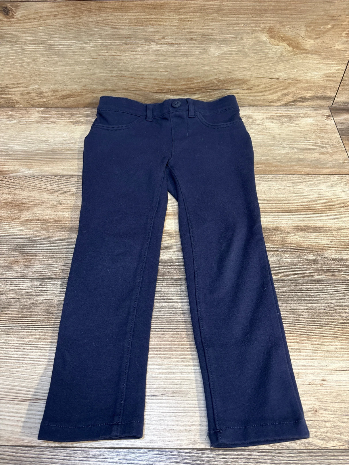 Top-down view of Children's Place navy ponte knit pull-on jeggings (size 5T) showcasing pull-on waistband and front pockets on a wood floor