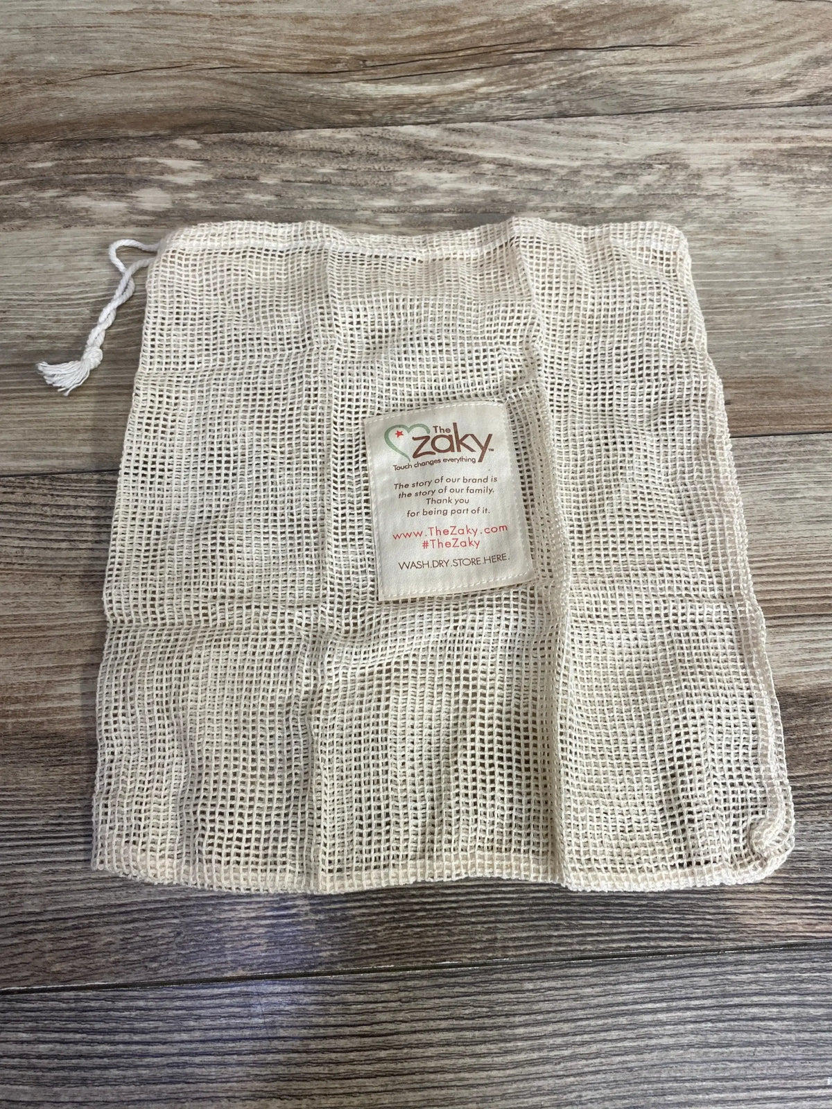 Reusable mesh laundry bag with drawstring on wood background, baby gear accessory