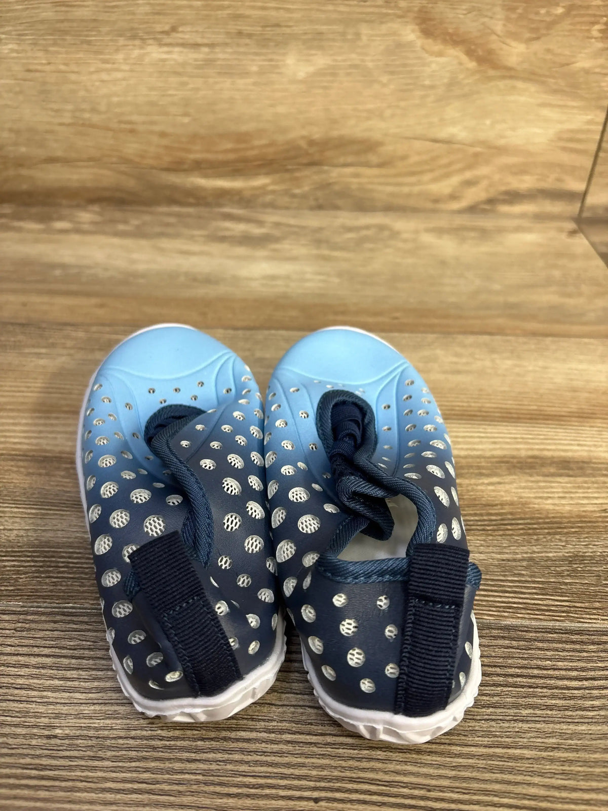 Top-front view of Fires Barefoot blue quick-dry toddler water shoes showing perforated upper, bungee laces, and white sole on wood background