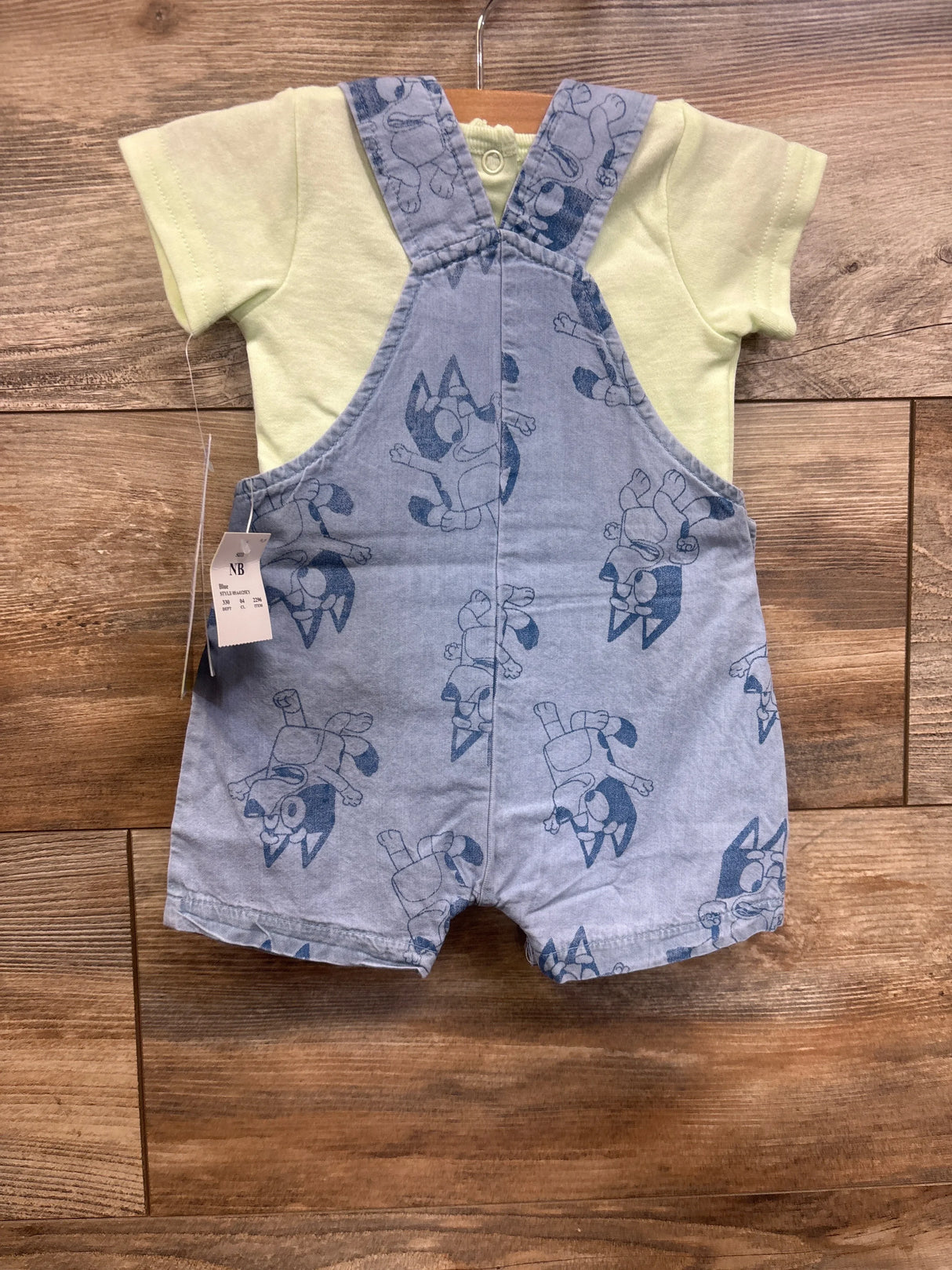 Baby romper set with yellow shirt and blue cartoon dog overalls on wood background