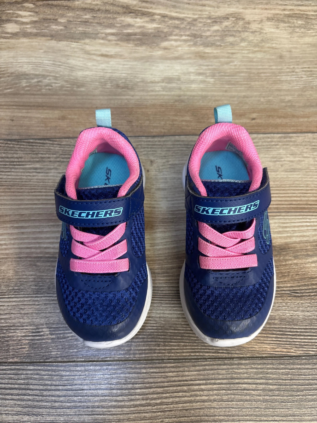 Blue and pink Skechers toddler sneakers with velcro straps on wood floor