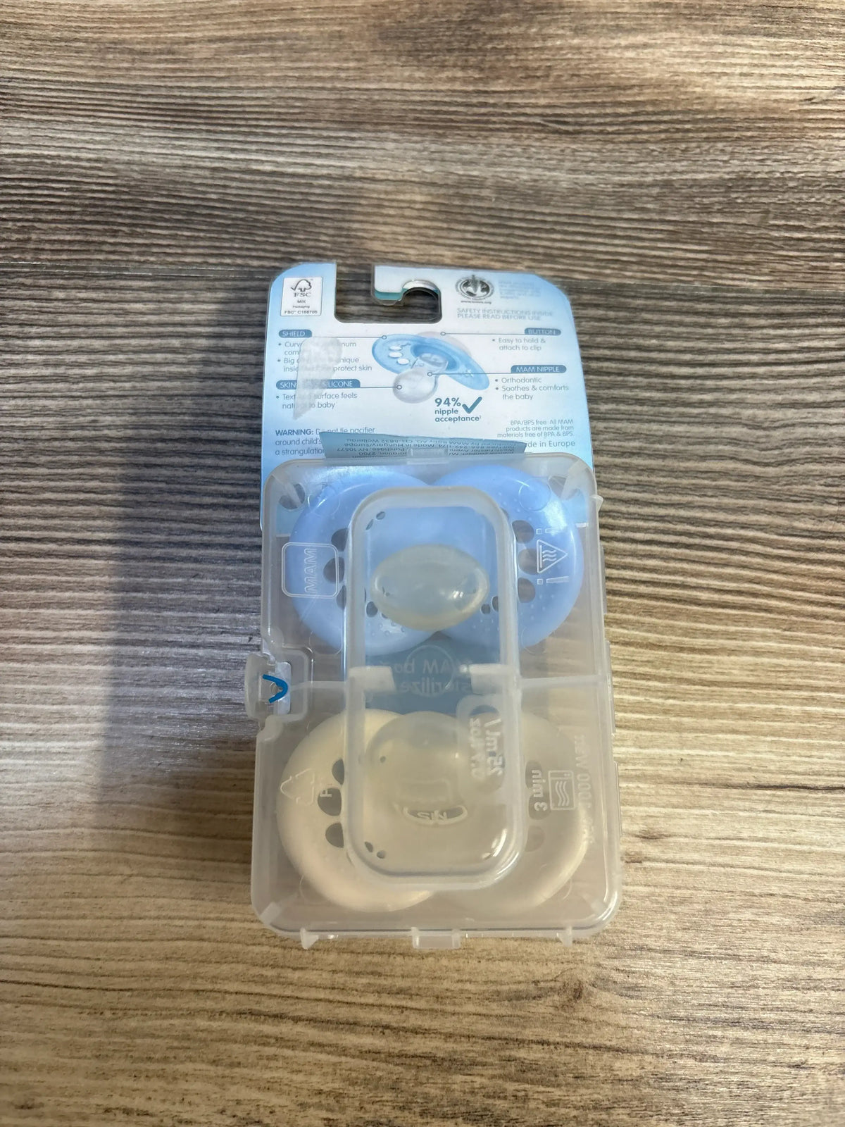 Pack of two baby pacifiers in blue and beige case on wood background