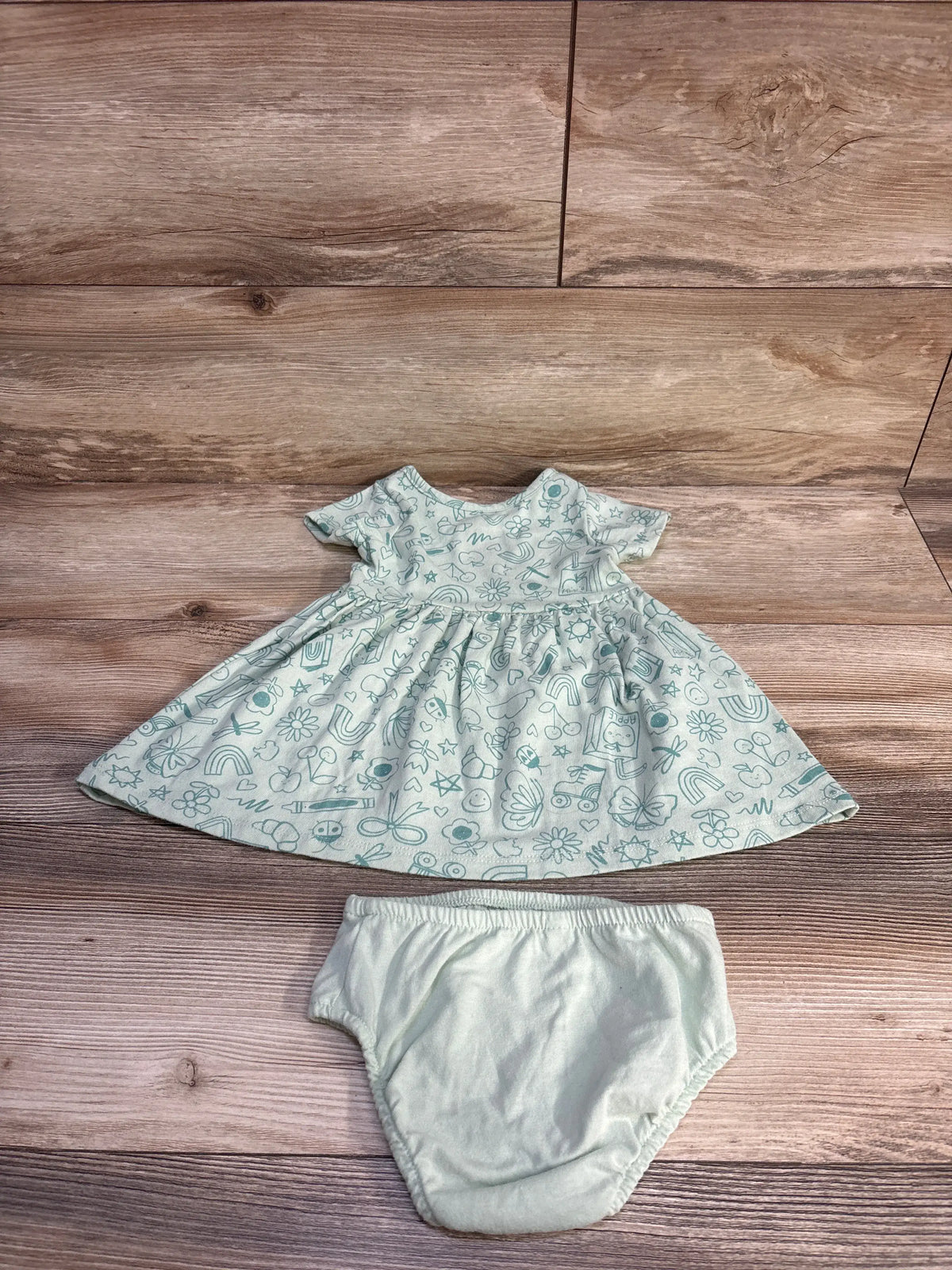 Front view of Cat & Jack 2pc dress and bloomers set showcasing green doodle print and matching bloomers on wood flooring
