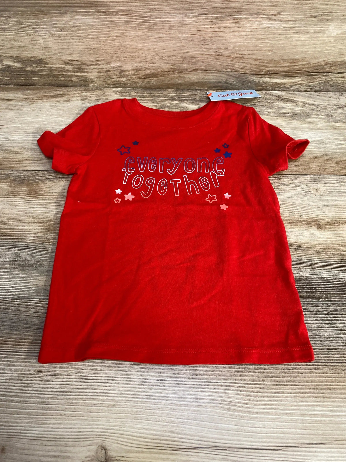 Flat lay of red Cat & Jack toddler tee size 2T showing everyone together graphic with star accents on wood background