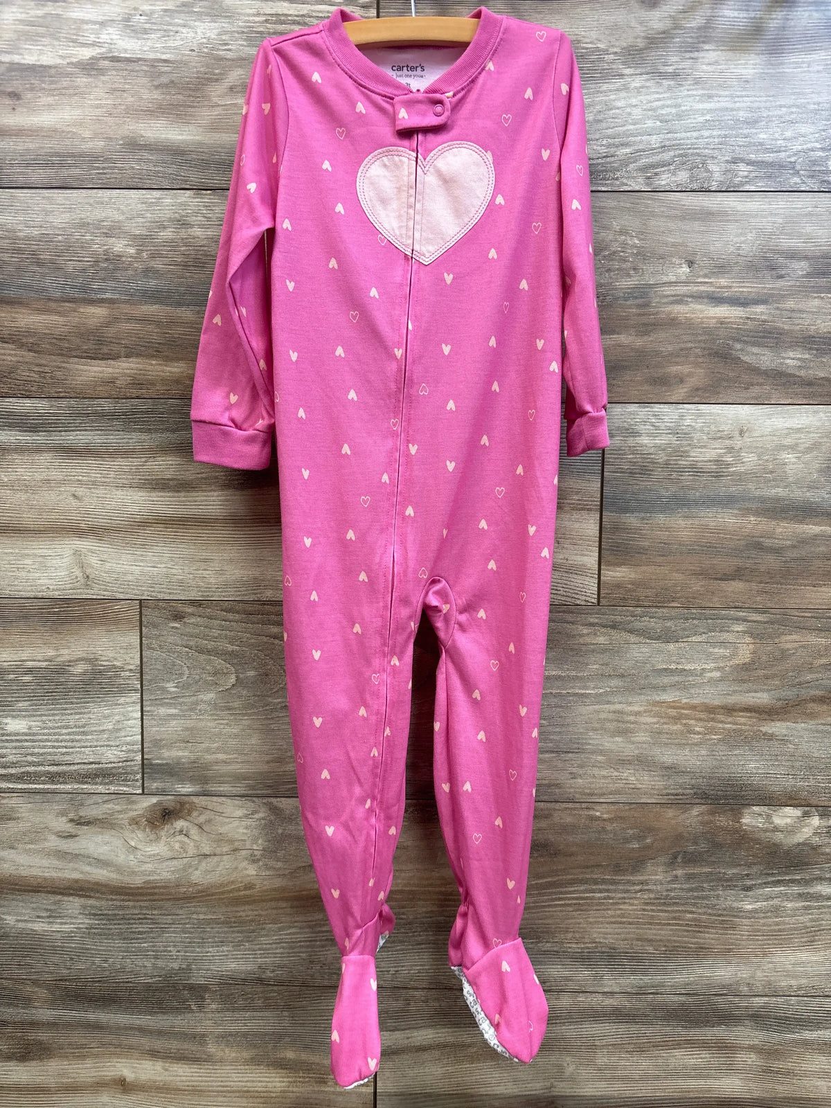 Front view of Just One You pink 3T sleeper with heart pattern, front zipper, and covered feet on wood background