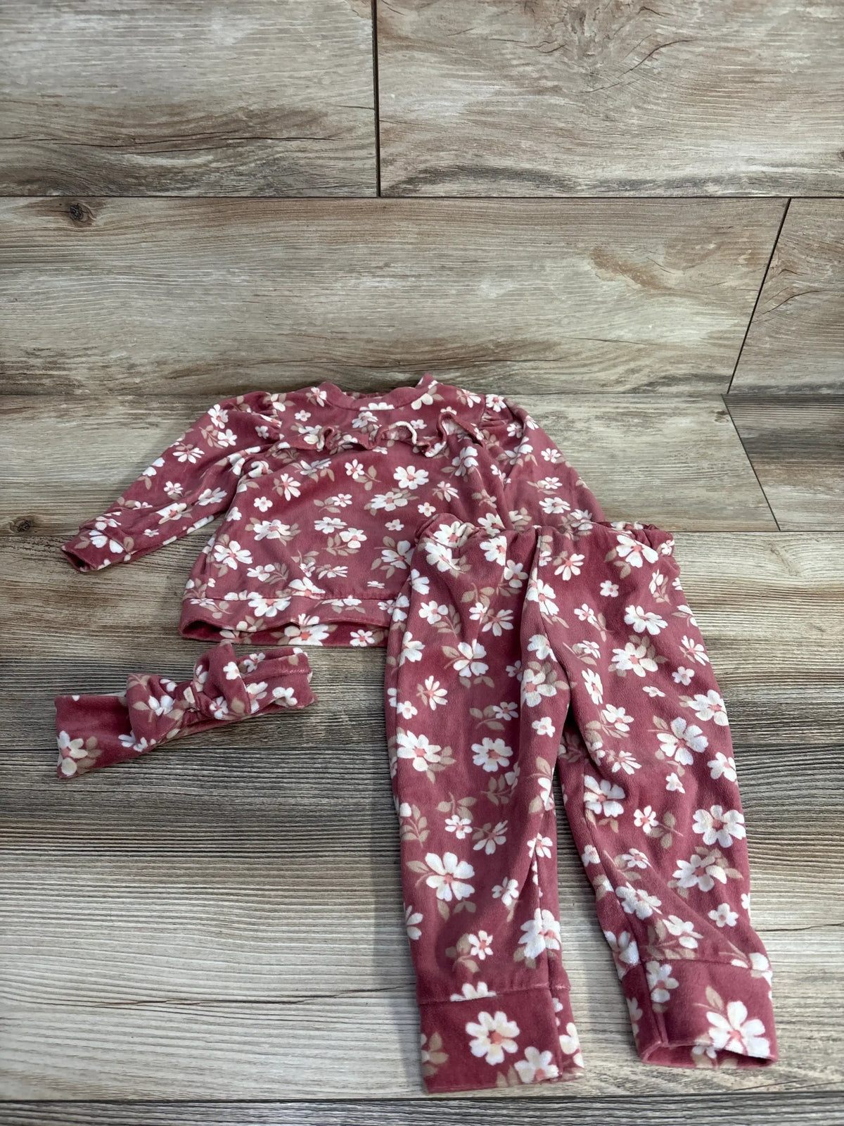 Pink floral baby outfit set with long sleeve top, pants, and matching headband on wood background