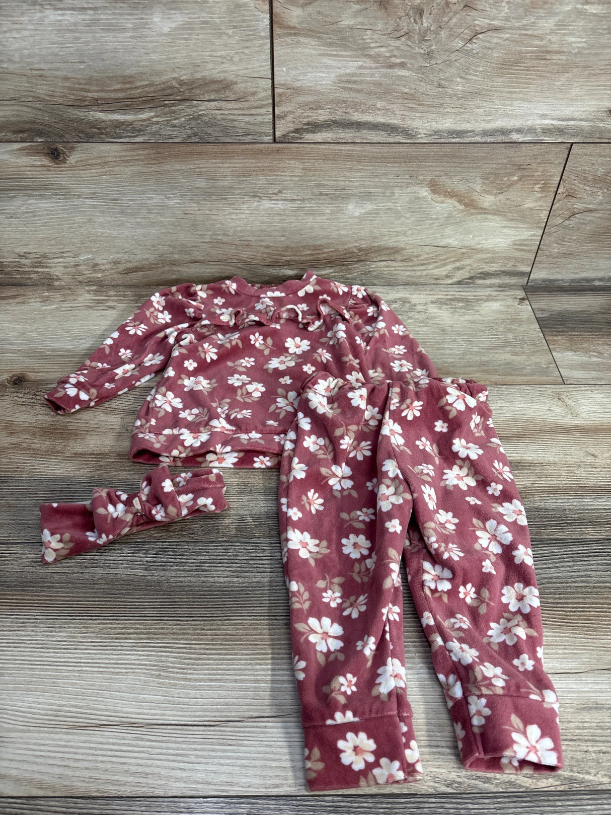Pink floral baby outfit set with long sleeve top, pants, and matching headband on wood background