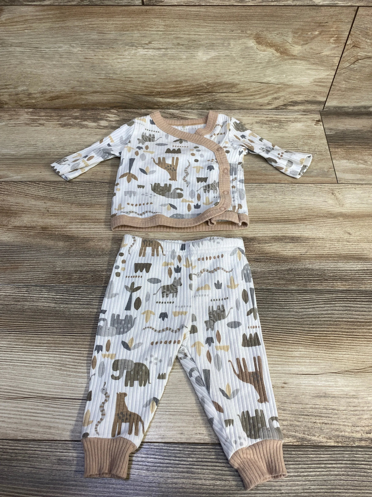 Flat lay of newborn ribbed kimono pajama set (0-3M) showing tan trim and beige-gray animal print on wood background