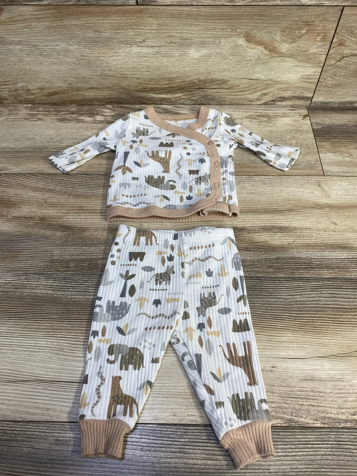Flat lay of newborn ribbed kimono pajama set (0-3M) showing tan trim and beige-gray animal print on wood background