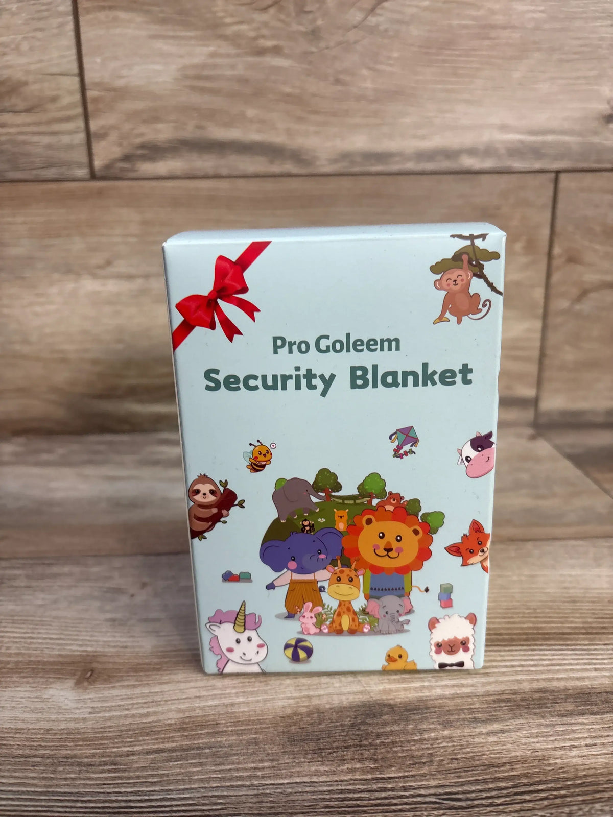 Front view of Pro Goleem elephant security blanket packaging with colorful animal illustrations on a wood surface