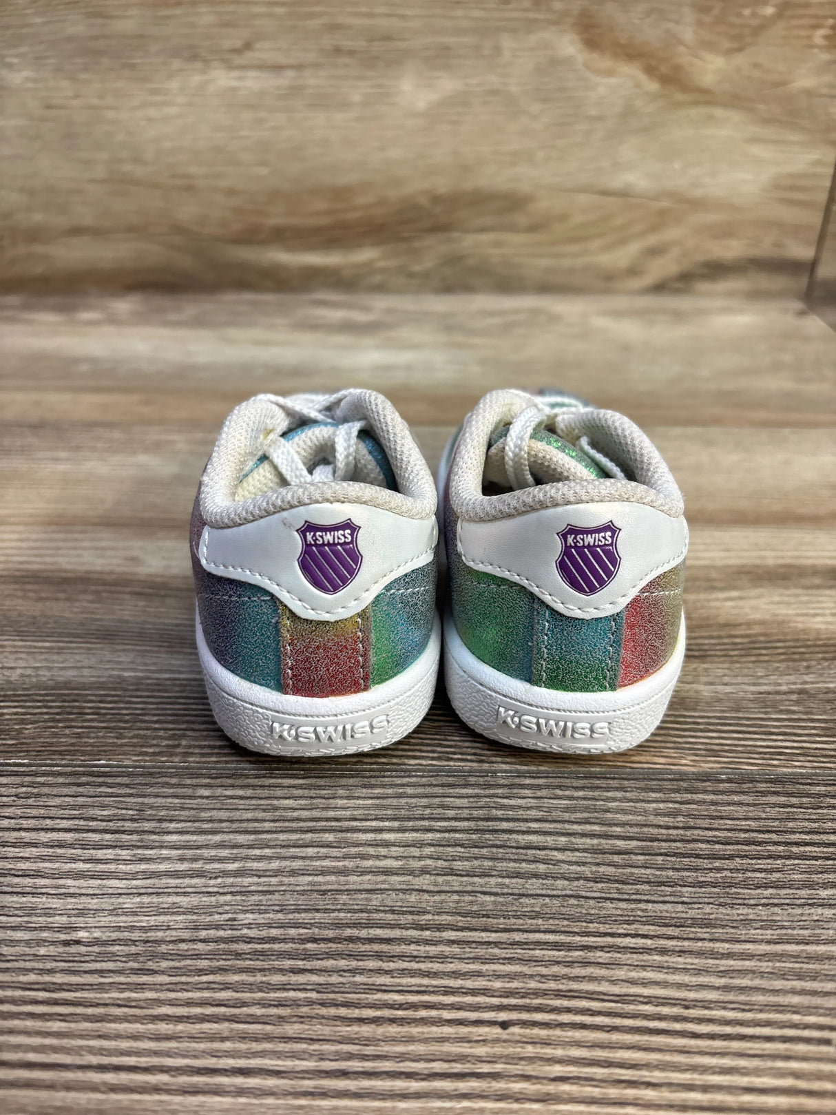 Rear view of K-Swiss Classic VN toddler sneakers size 7C showing rainbow glitter panels and purple K-Swiss shield on a wood surface