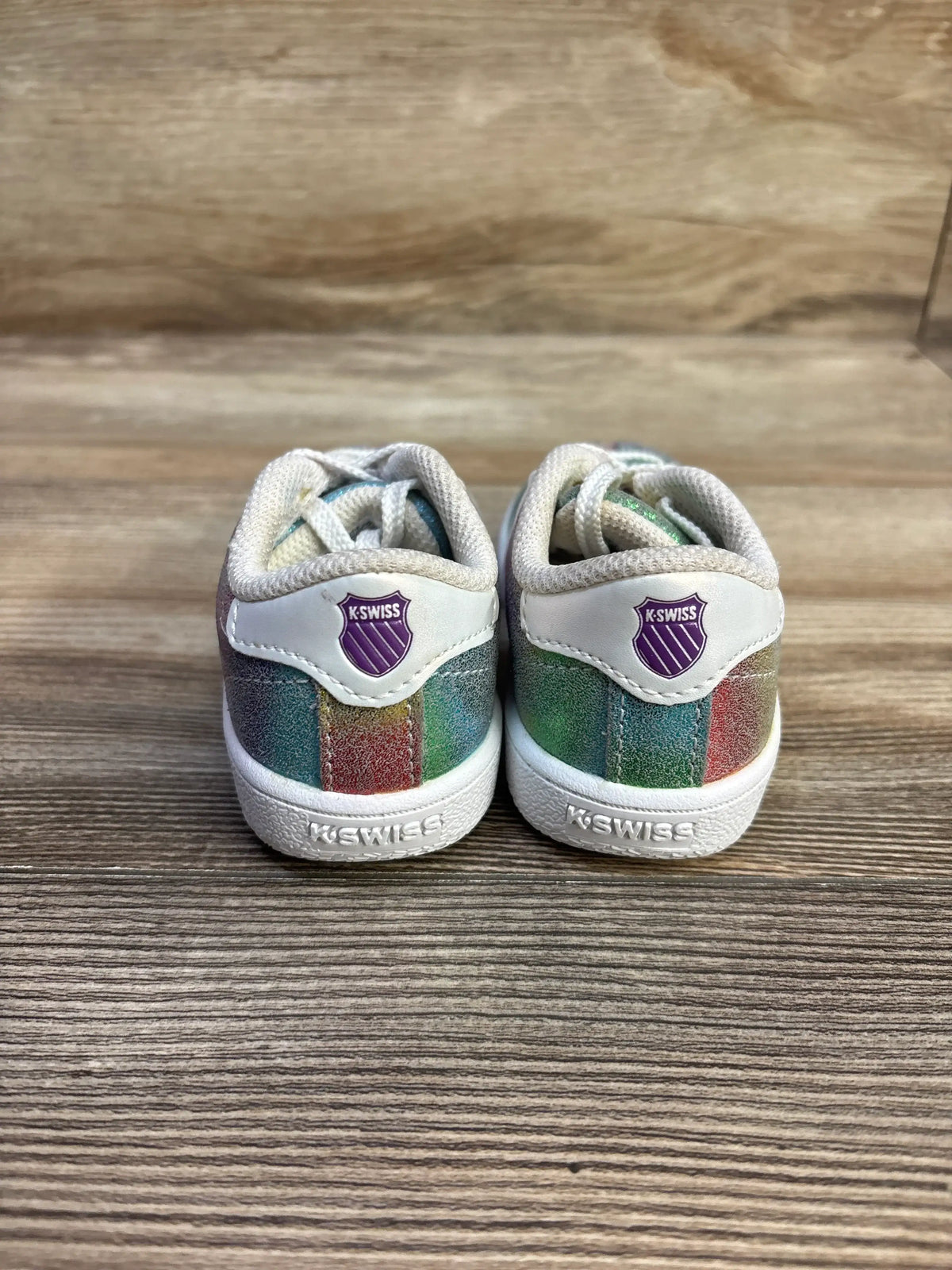 Rear view of K-Swiss Classic VN toddler sneakers size 7C showing rainbow glitter panels and purple K-Swiss shield on a wood surface