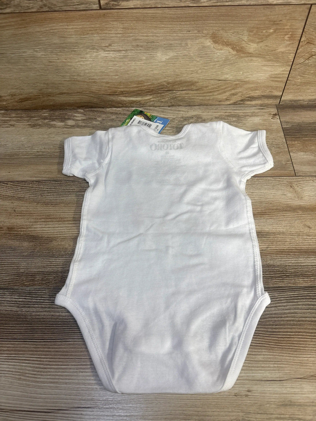 Back view of a white Boxlunch My Neighbor Totoro bodysuit showcasing short sleeves on a wood-patterned floor