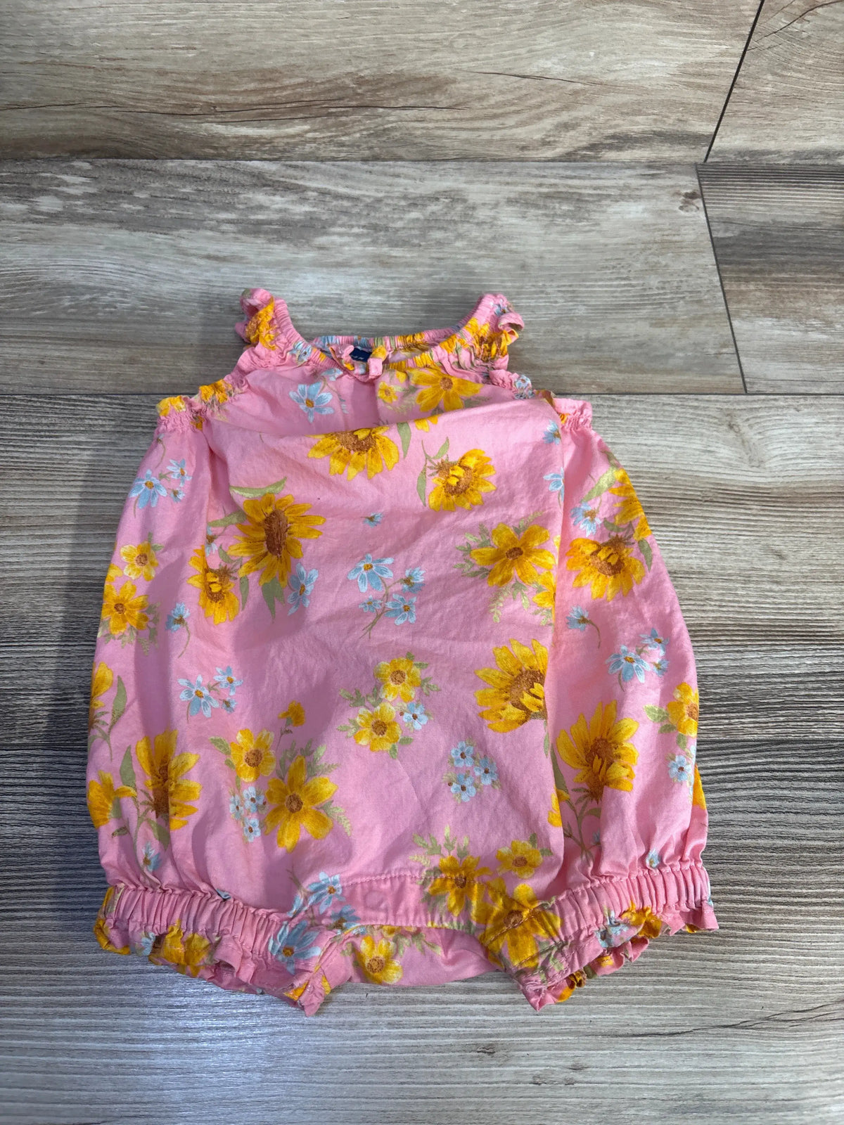 Front view of Old Navy sleeveless floral shortie romper showcasing pink floral print with a wood-look background