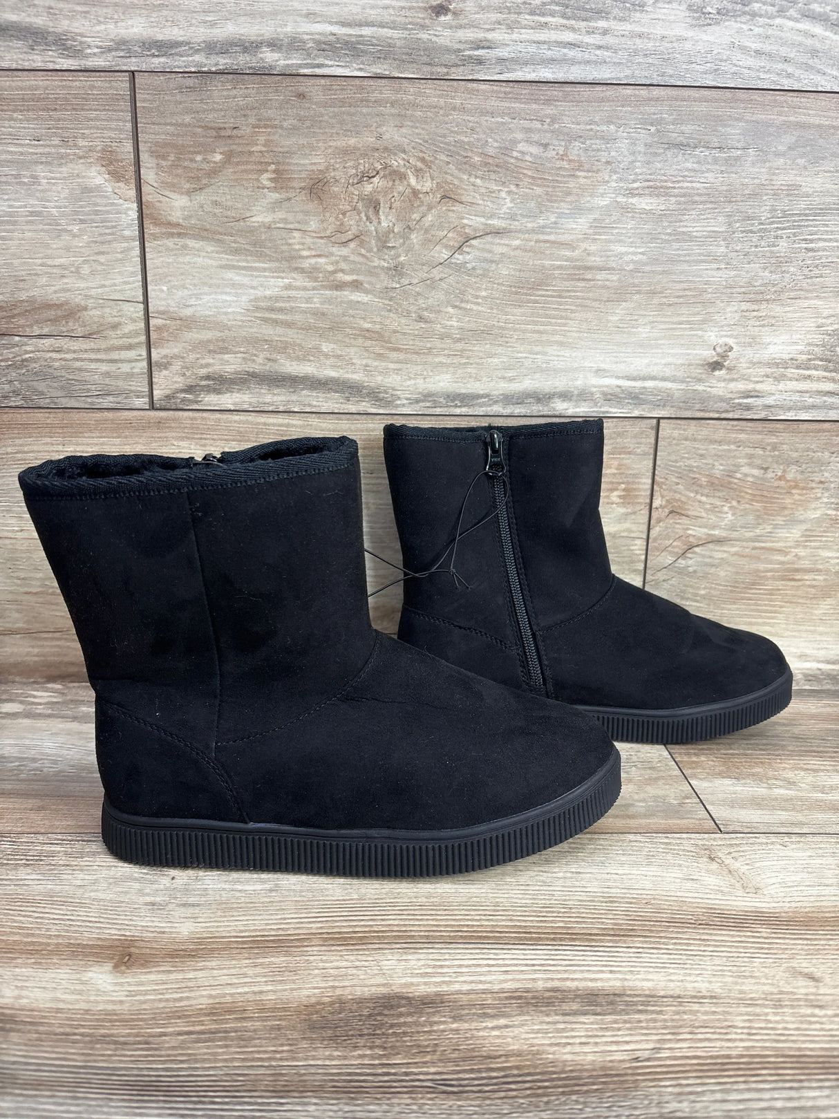 Black suede kids winter boots with side zipper on wood background