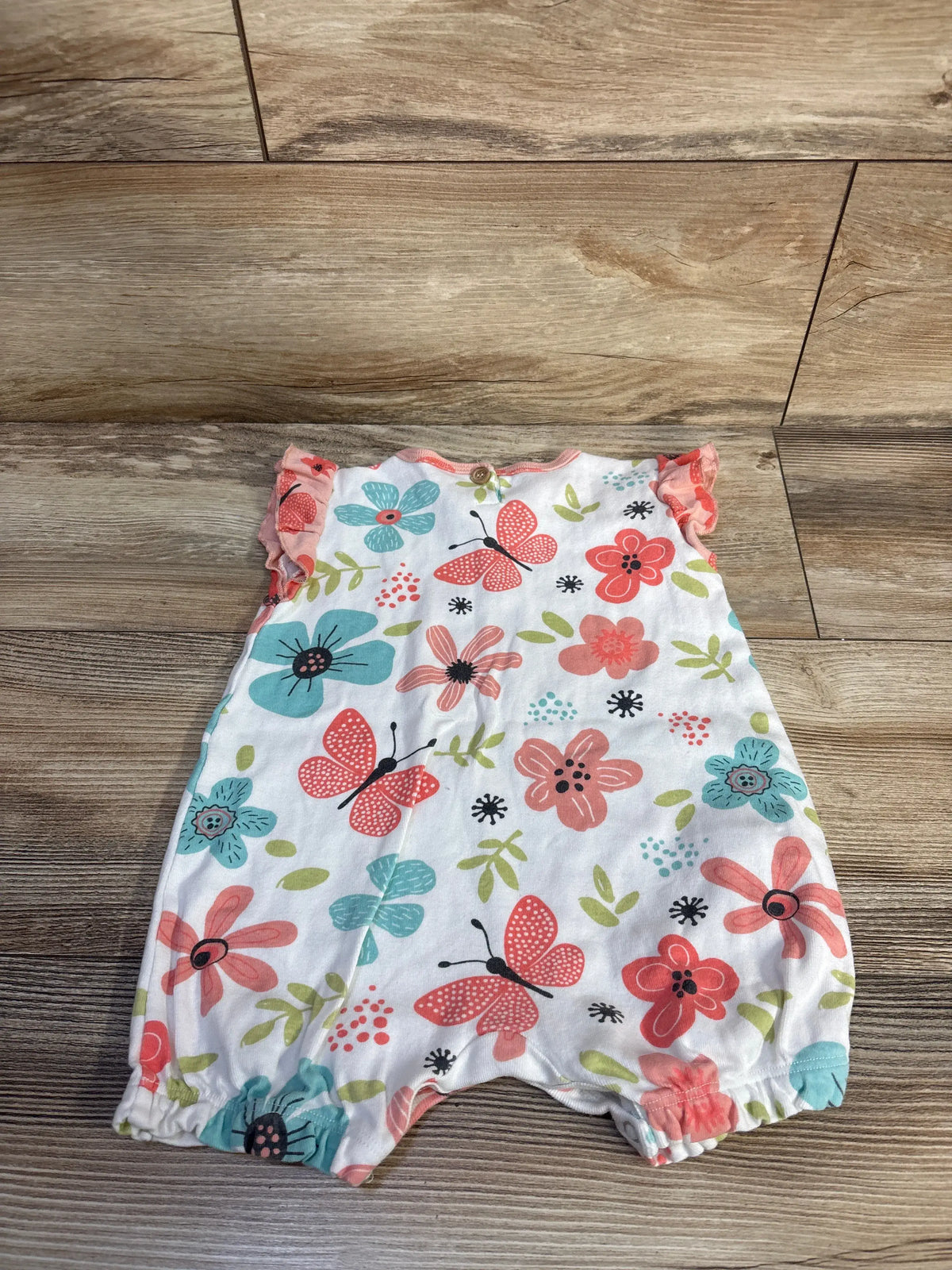 Tesa Babe baby romper with pink and blue floral and butterfly print on a wood background
