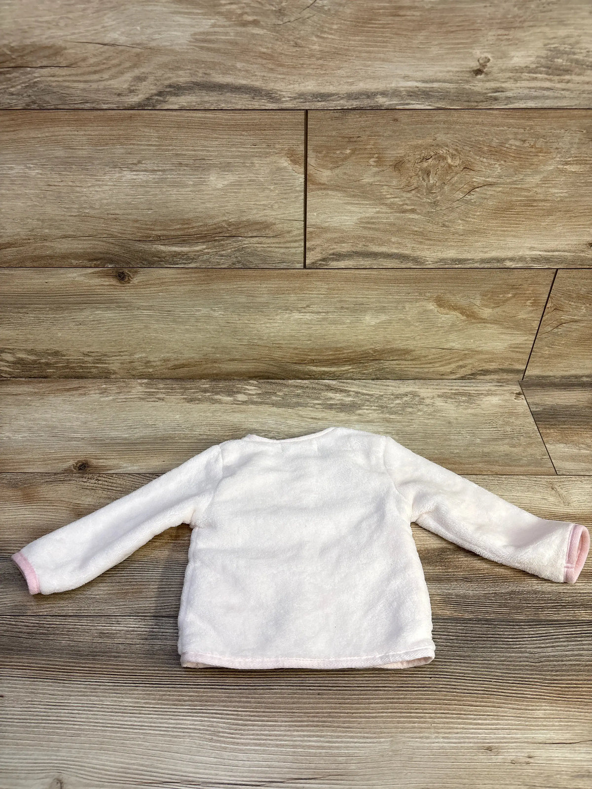 Flat view of Starting Out plush button-up cardigan in pink, showcasing its soft texture and long sleeves on a wood floor