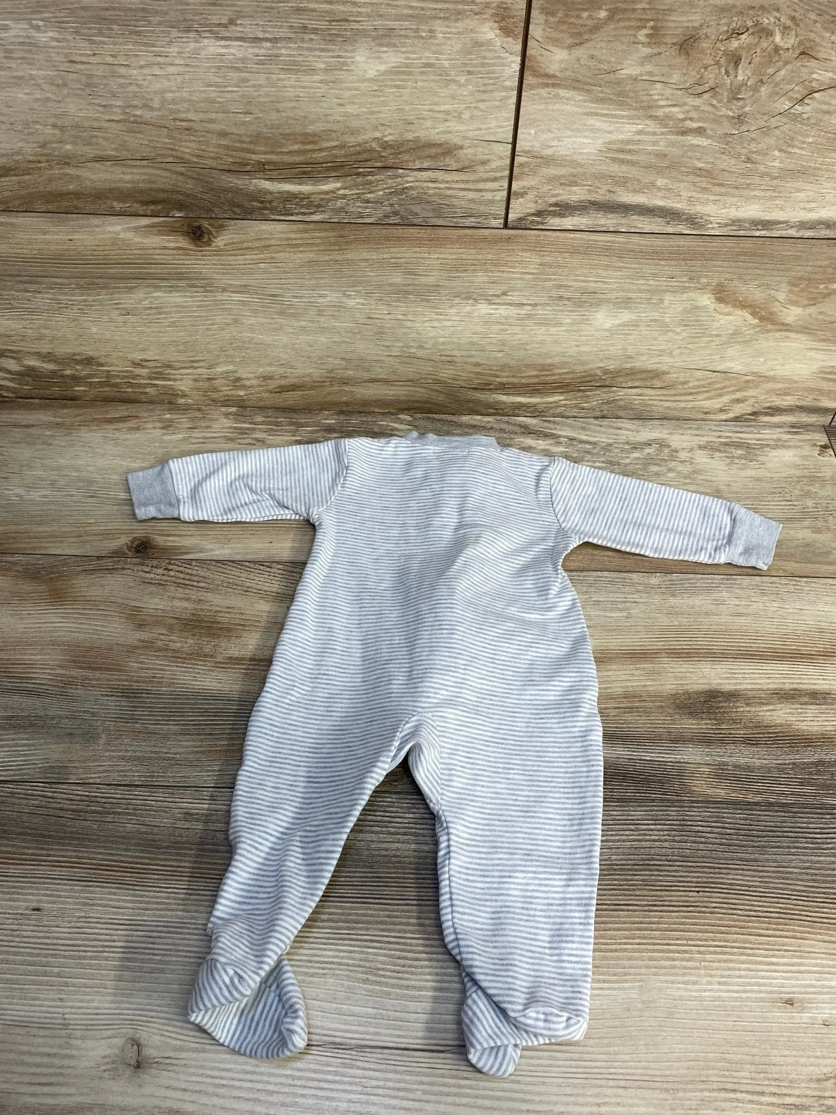 Gray striped baby footed onesie on wood floor