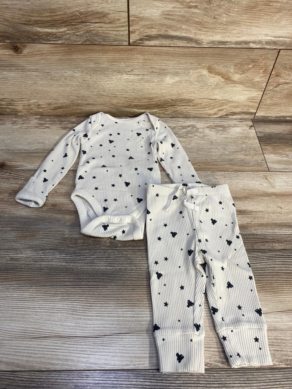 White ribbed baby onesie and pants set with black stars and bunny patterns on wooden floor