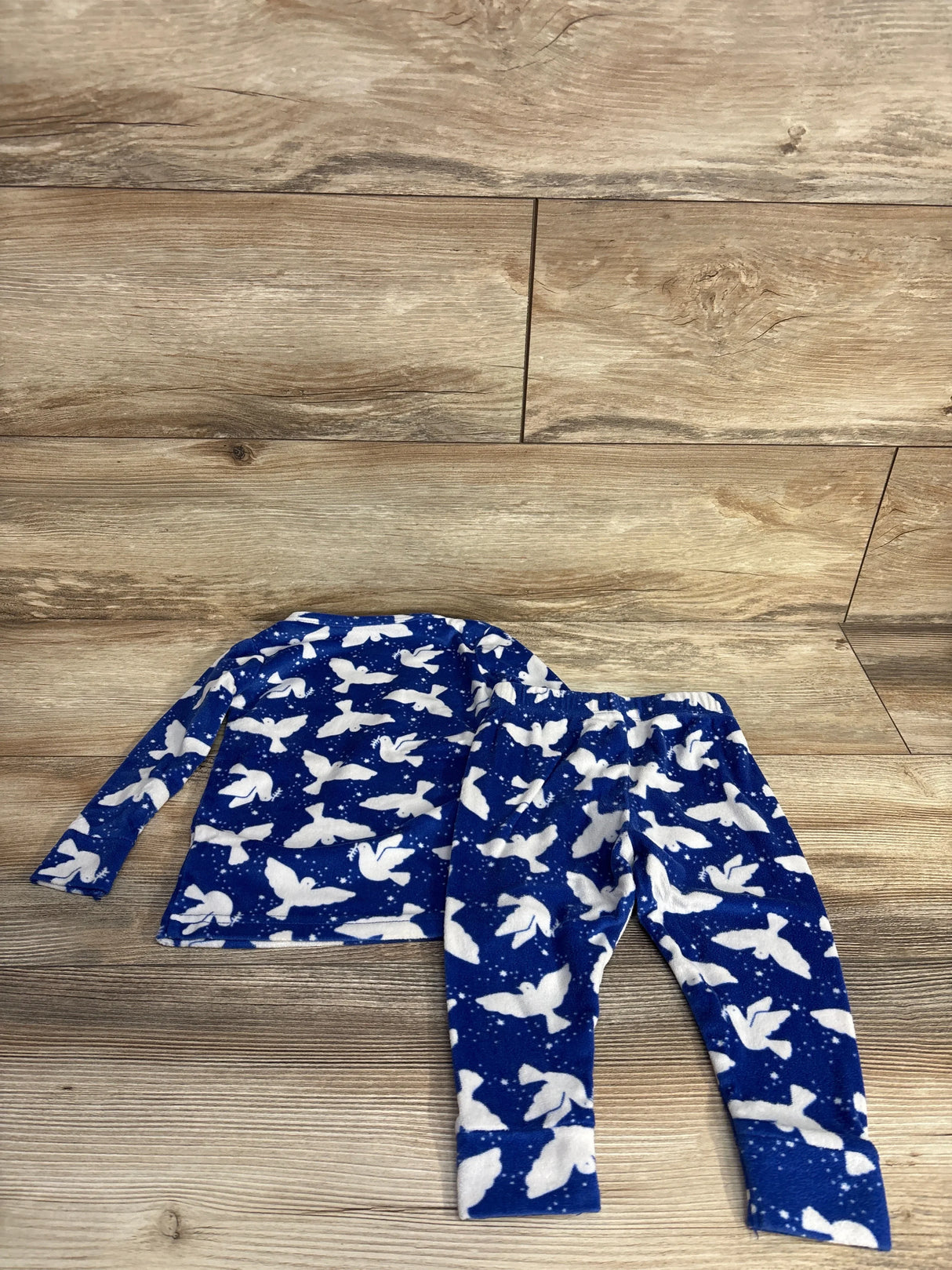 Blue fleece pajamas with white bird patterns laid on wooden floor