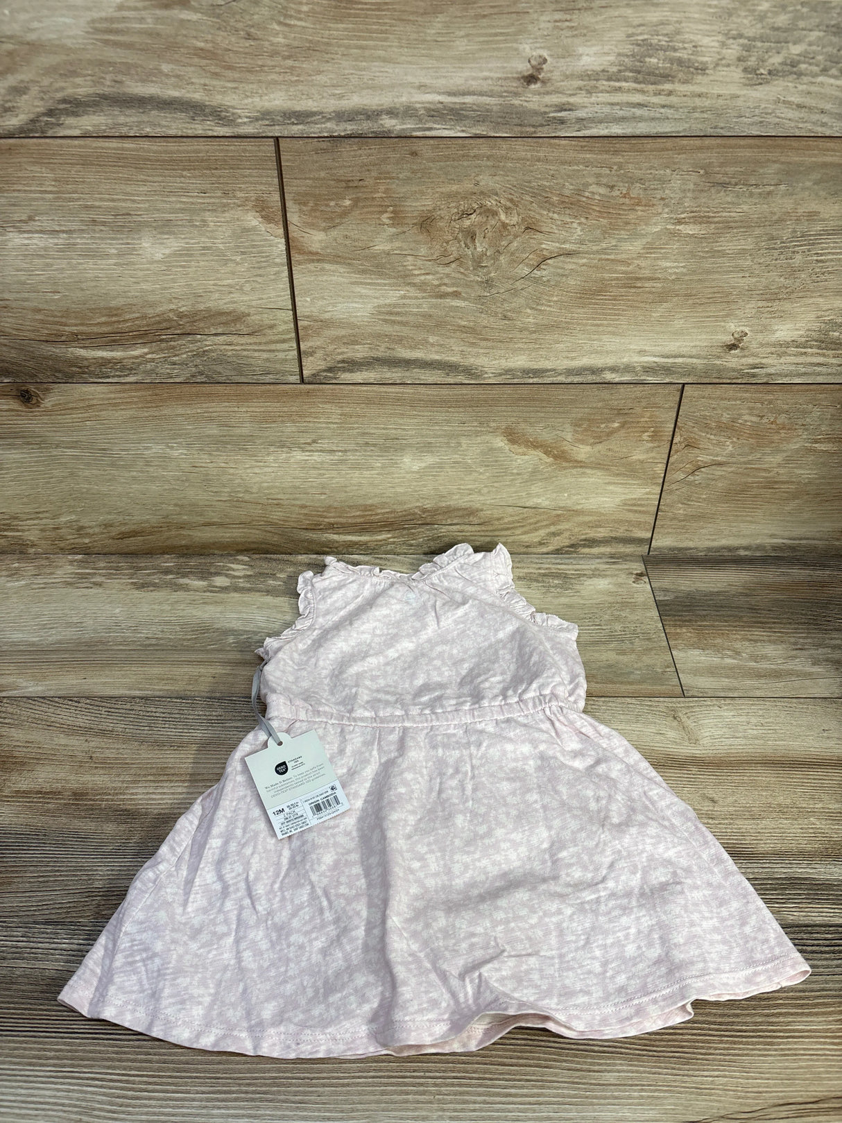 Flat lay of Cloud Island pink tank dress showcasing ruffled cap sleeves and subtle heathered pattern with wood plank background