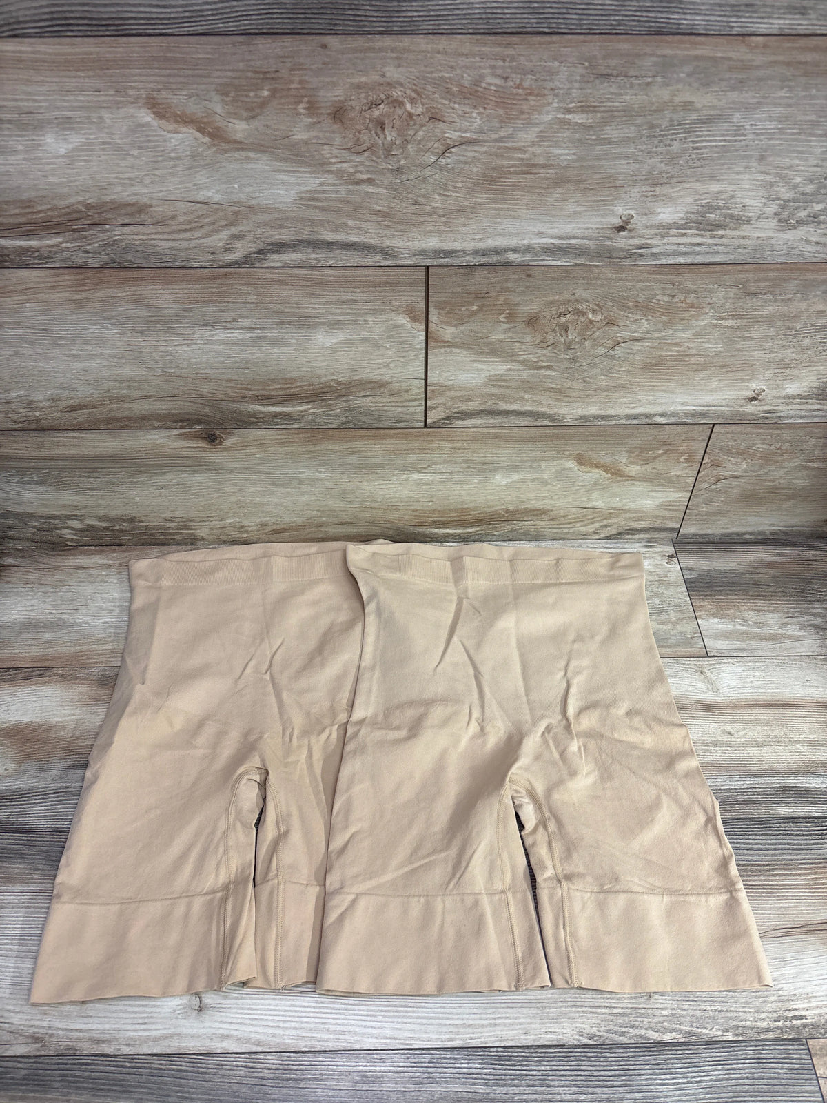 Two pairs of beige seamless maternity shapewear shorts by Me n Mommy To Be on a wood background