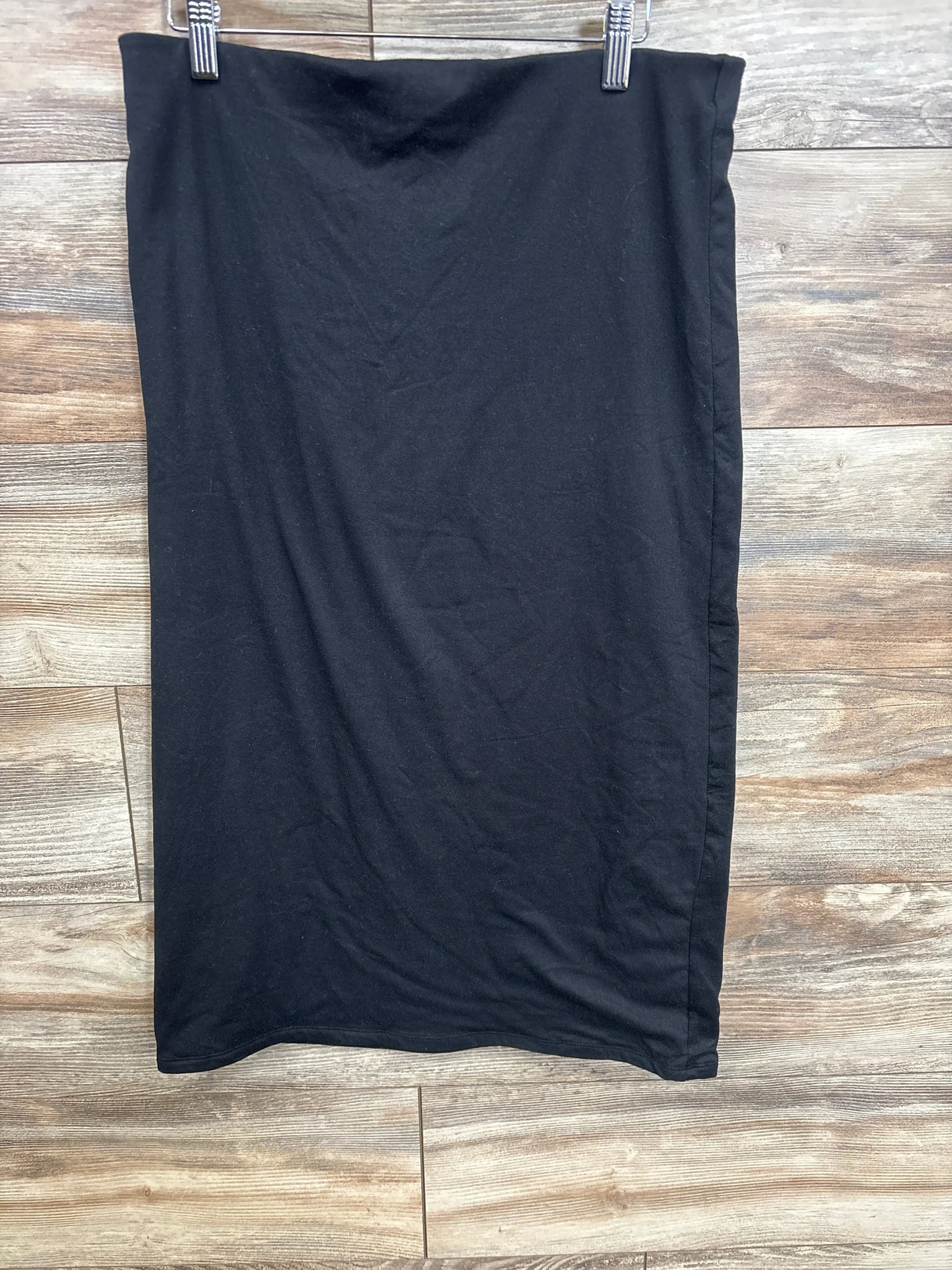 Black maternity tube skirt hanging on wooden background at kids' resale store