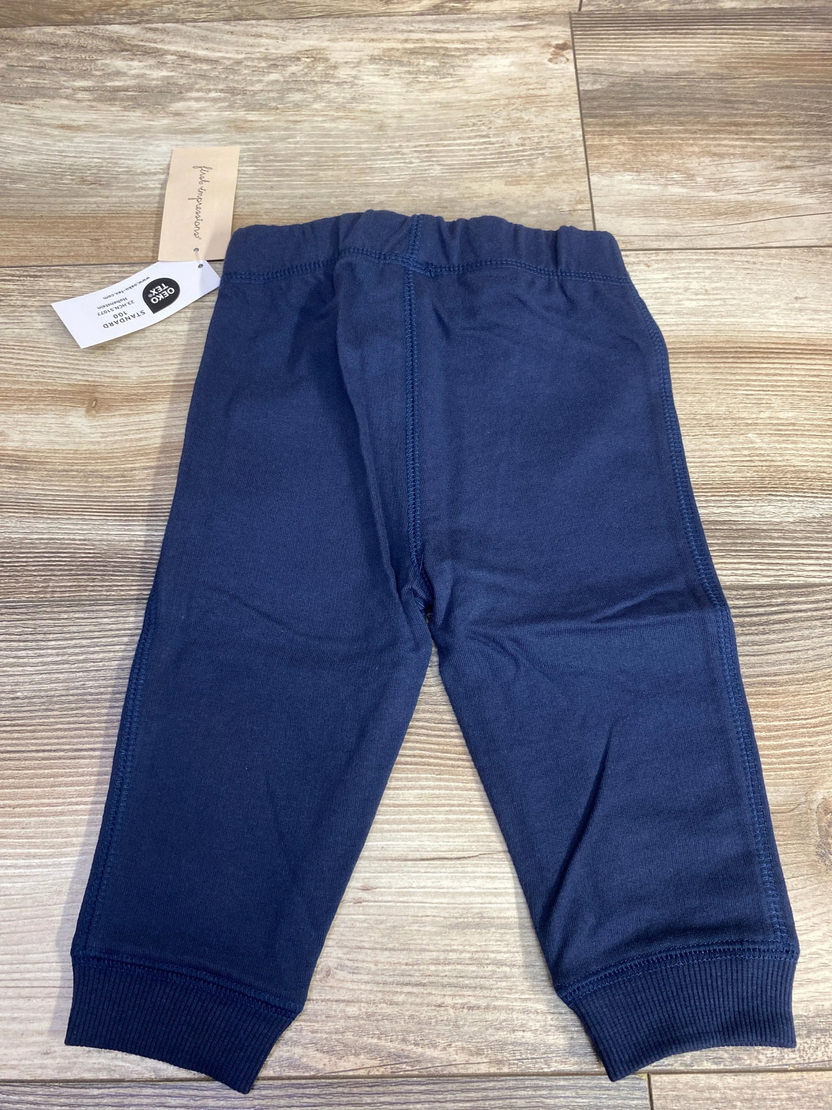 Navy blue baby pants with elastic waistband displayed on wood floor