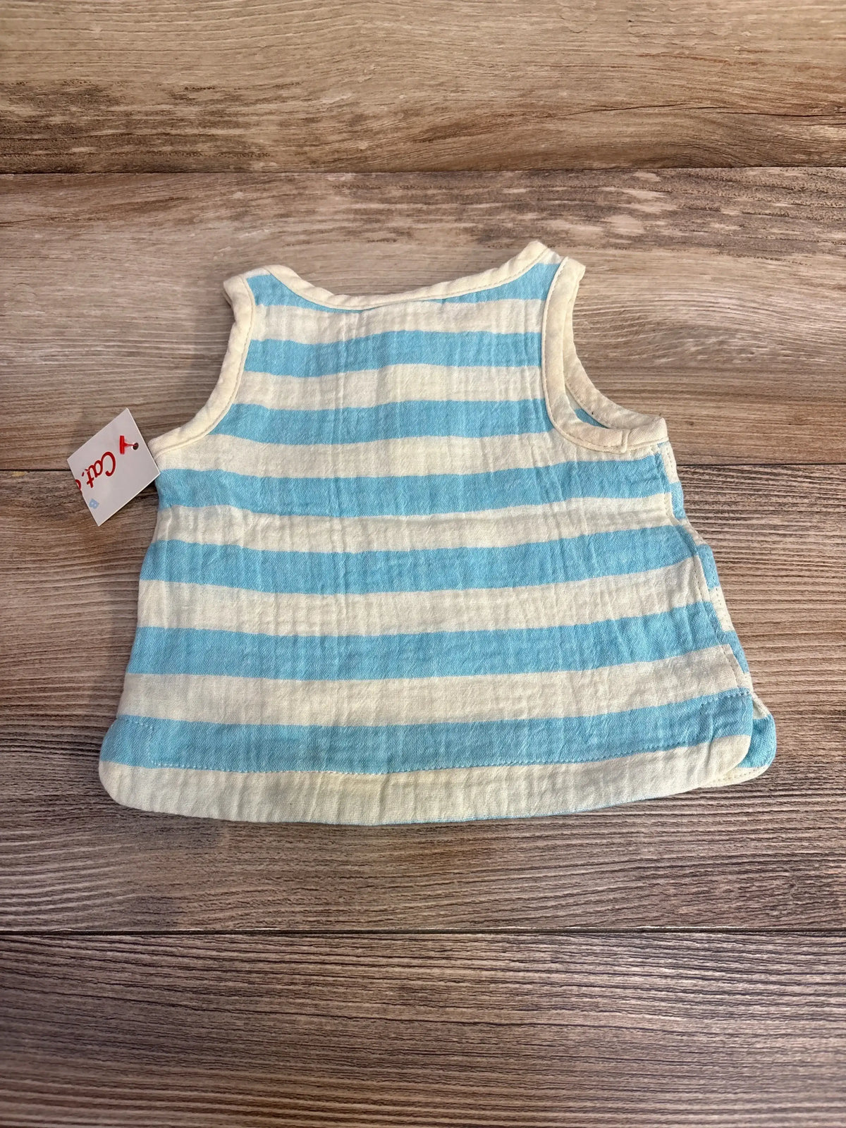 Flat lay of newborn blue and white striped sleeveless tank top showcasing soft cotton texture and sleeveless design, size 0-3M, on wood background