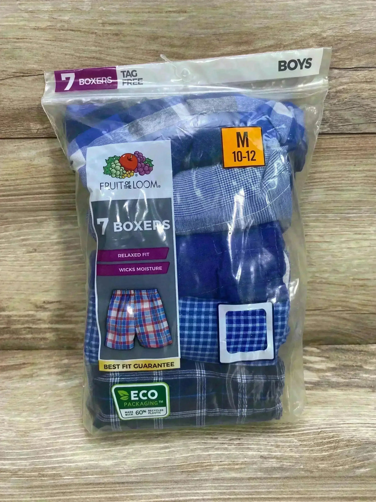 Front view of Fruit of the Loom boys 7-pack boxers in clear bag showing assorted blue plaids, size M 10-12 on wood background