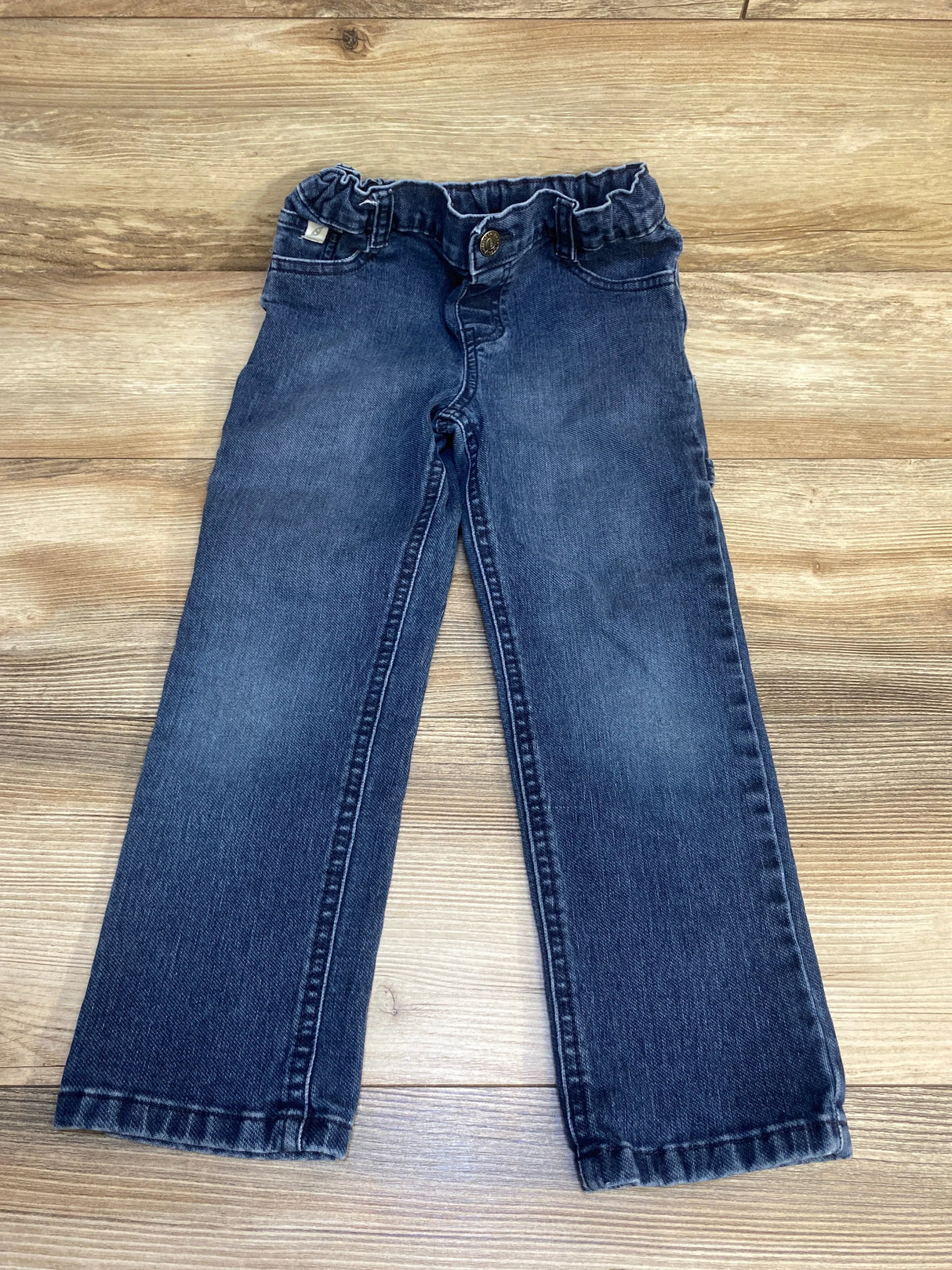 Dark wash kids jeans with elastic waistband on wood floor background