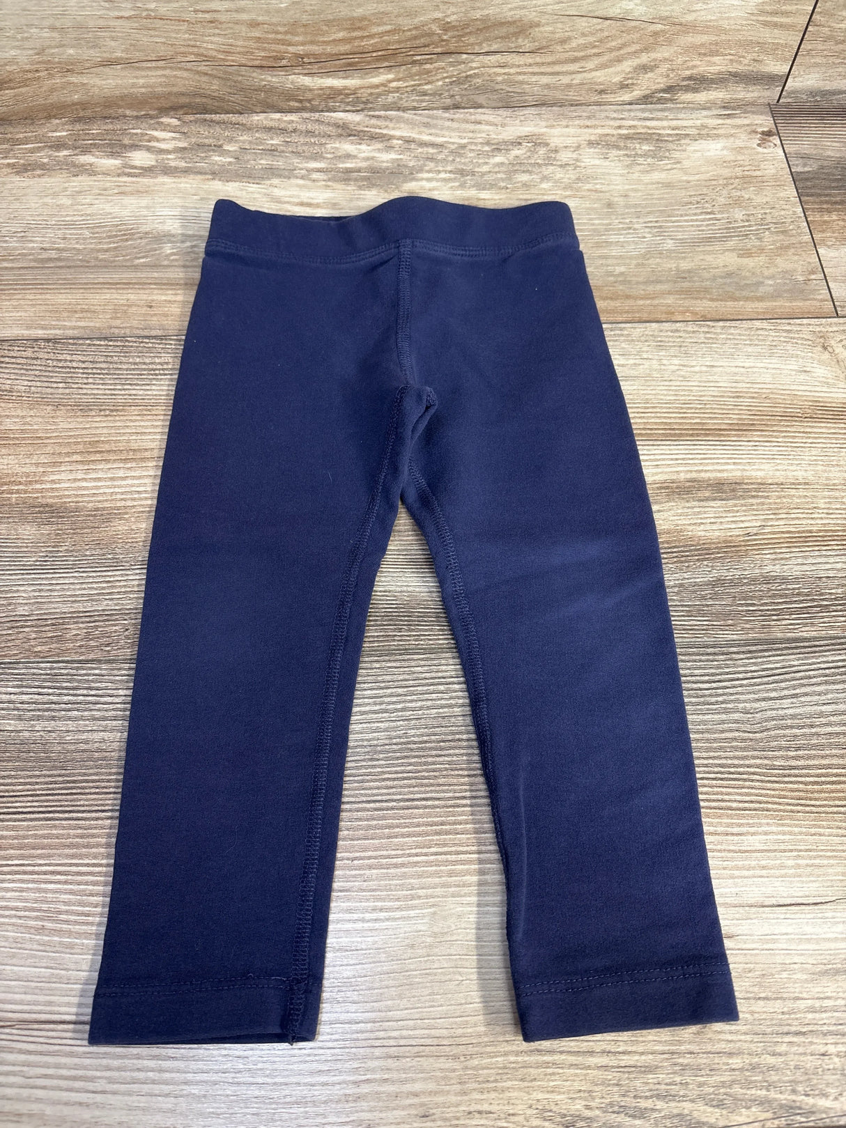 Navy blue toddler leggings on wood floor background