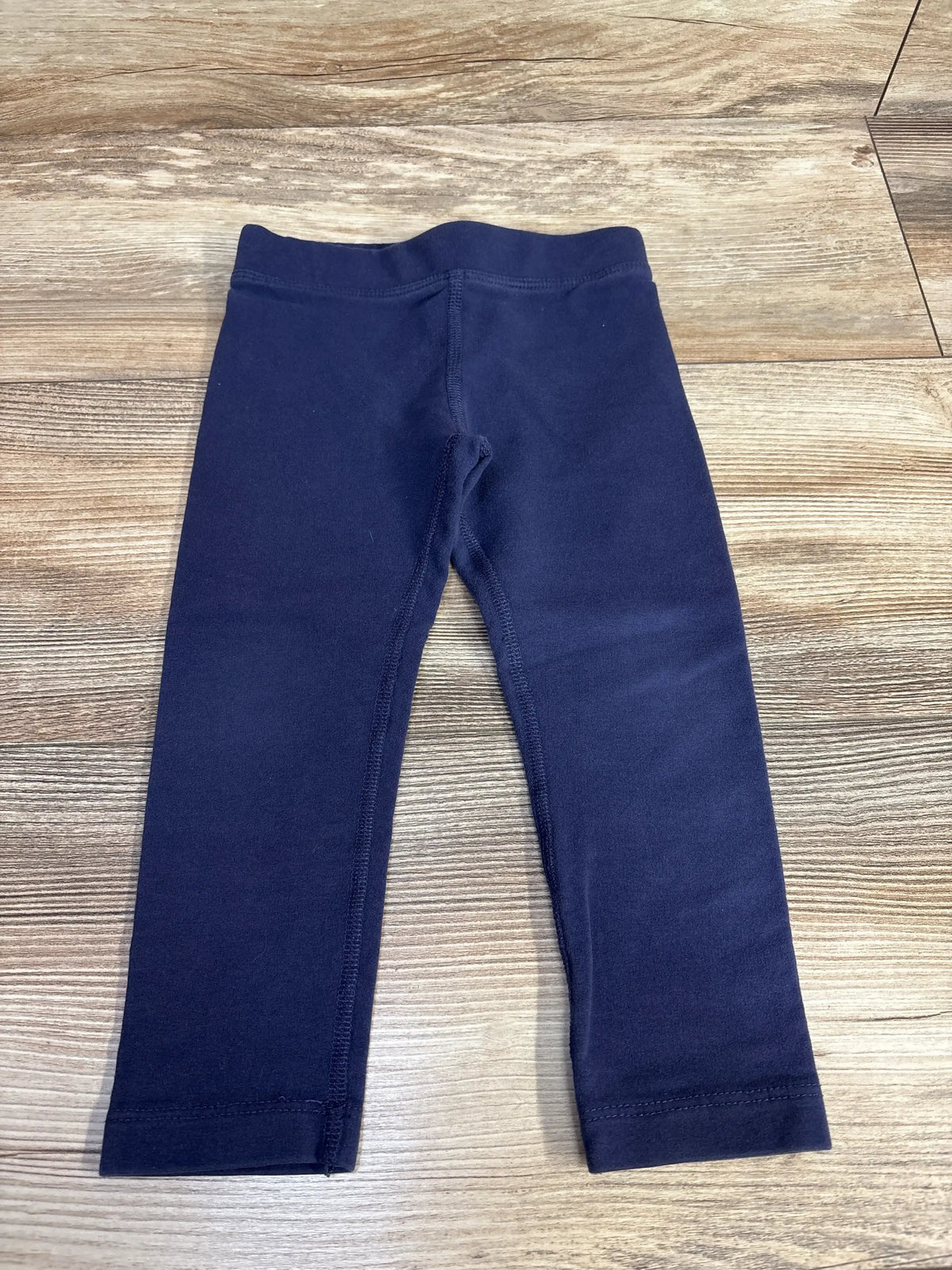 Navy blue toddler leggings on wood floor background
