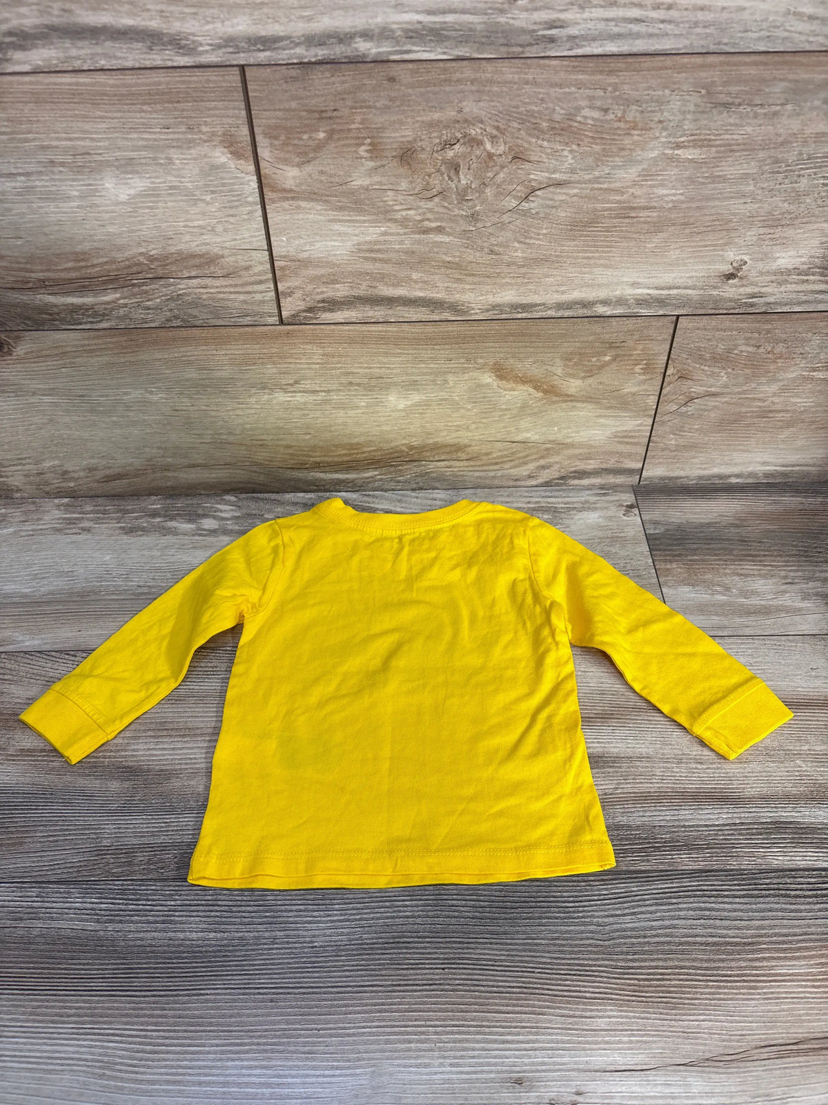Back view of Tommy Hilfiger logo shirt showcasing bright yellow long sleeves and relaxed fit on a wood-look floor