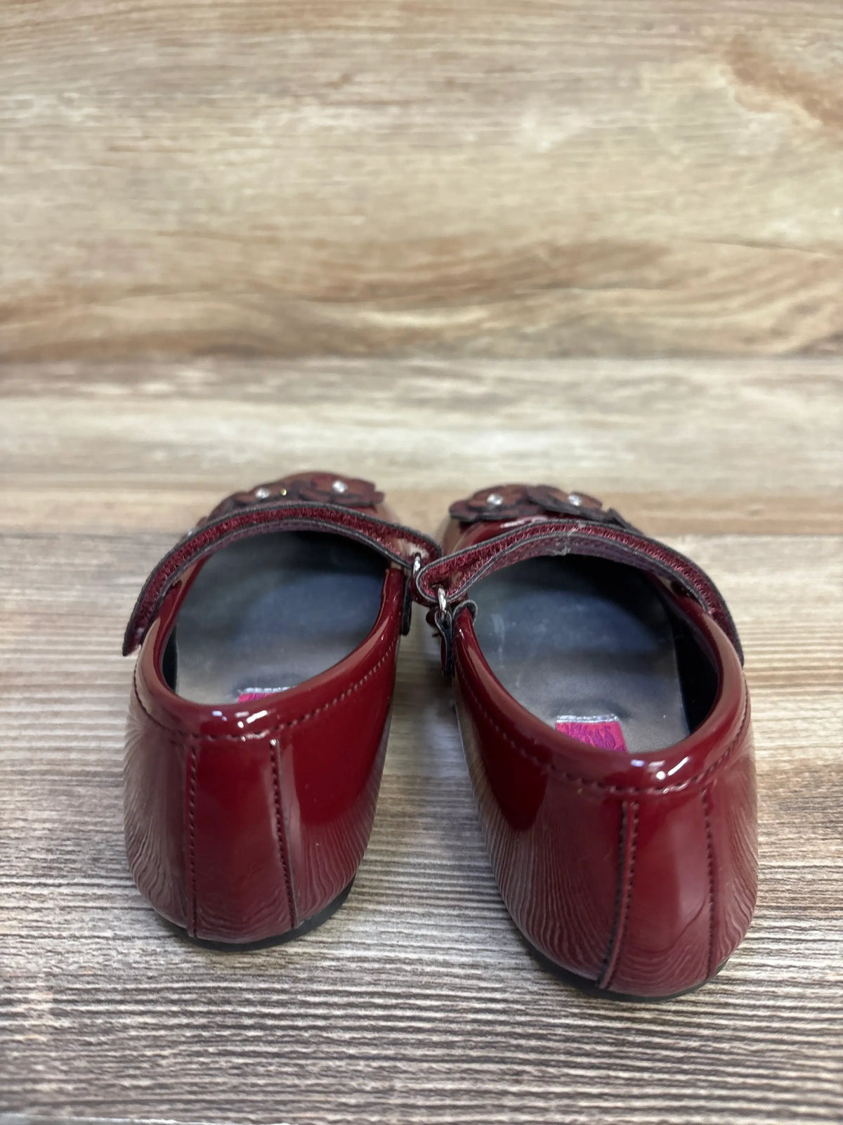 Rear view of Rachel Shoes Lil’ Abelina flats showcasing glossy burgundy patent leather, halo straps, and floral vamp accents
