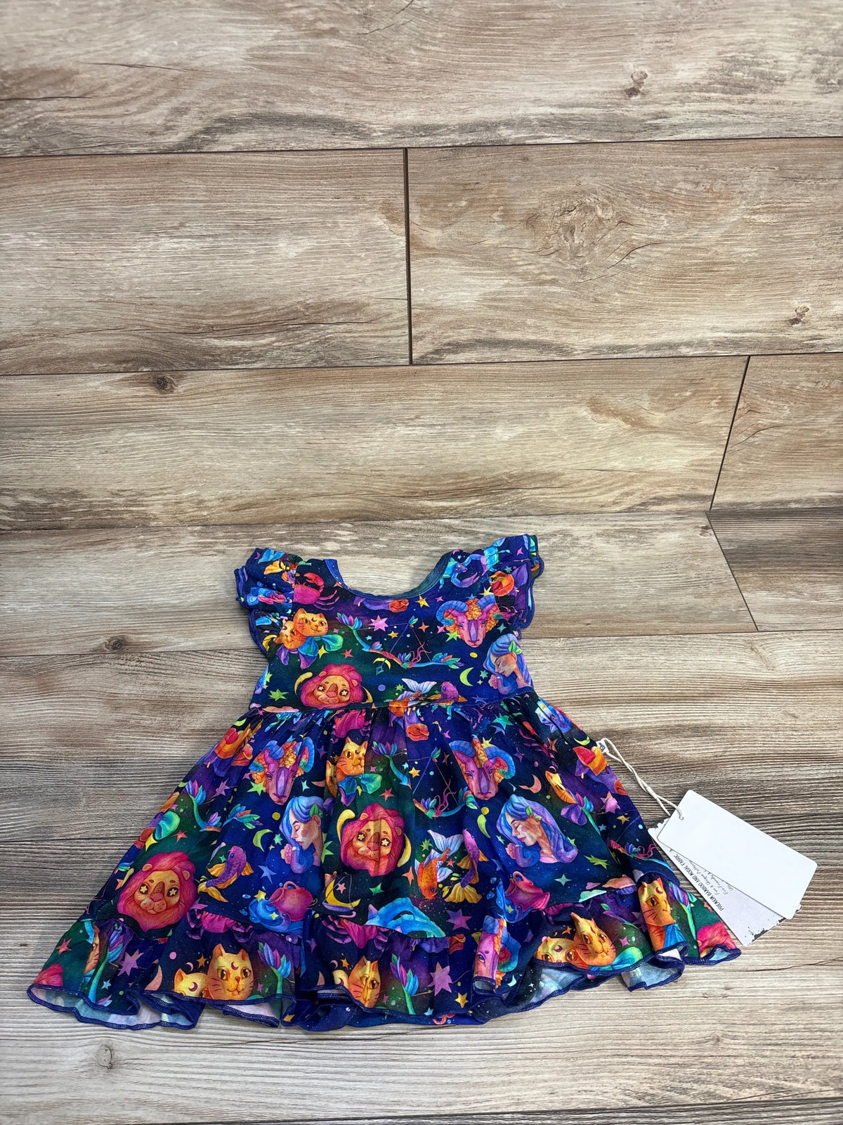 Front view of navy Jammie Session bamboo bodysuit twirl dress showcasing colorful cosmic print and full skirt on a wood-look floor