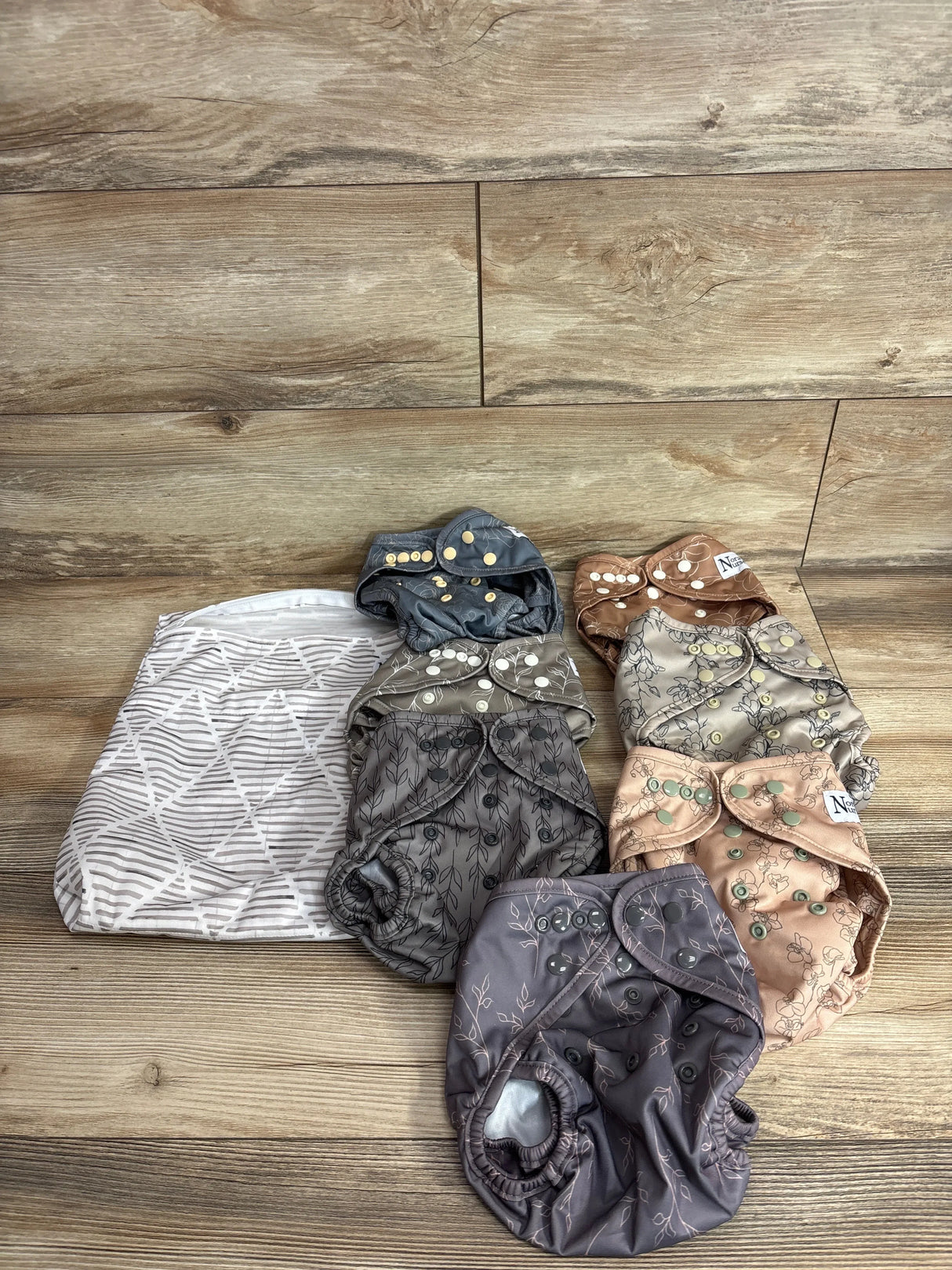 Top view of Nora’s Nursery cloth swim diaper covers and wet bag showcasing assorted patterns and snap closures